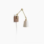 Swing arm ceramic wall lamp with brass hardware and walnut wood base on white wall - front view