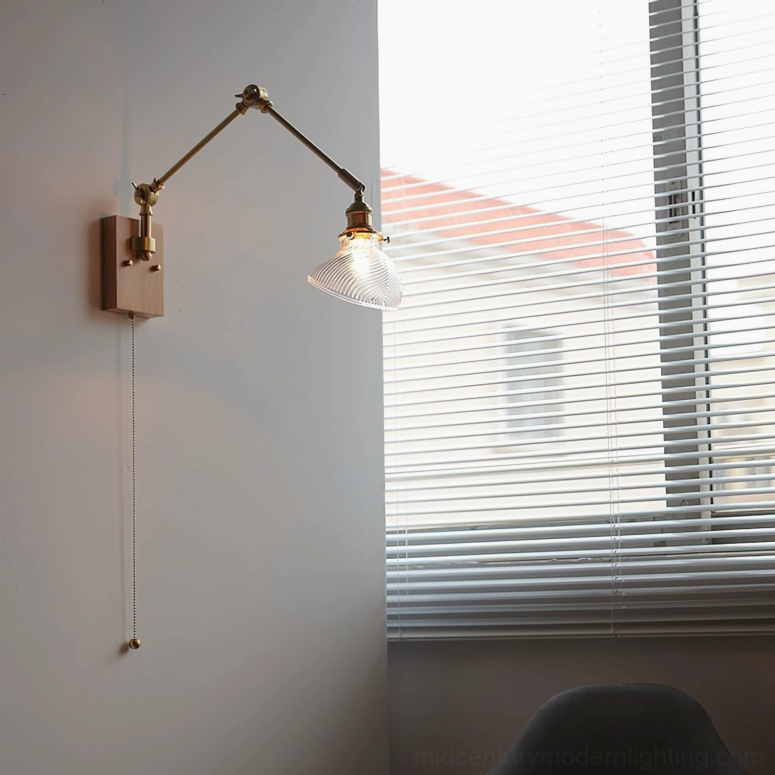 Adjustable swing arm wall lamp with clear ribbed glass shade and light wood finish in modern home with louvered window