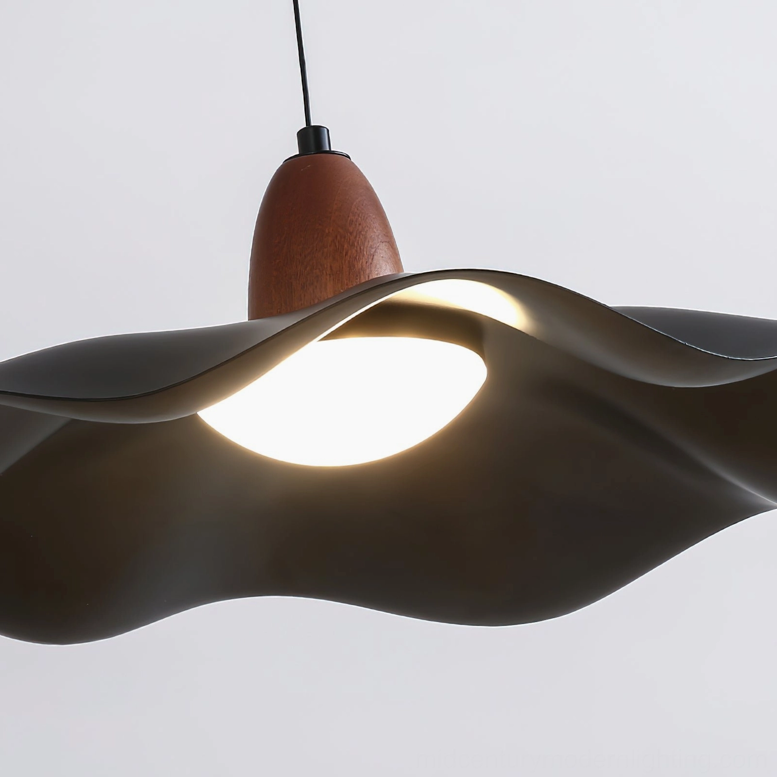 Matte black wavy acrylic shade of swing arm pendant light showing sculptural form and contemporary design