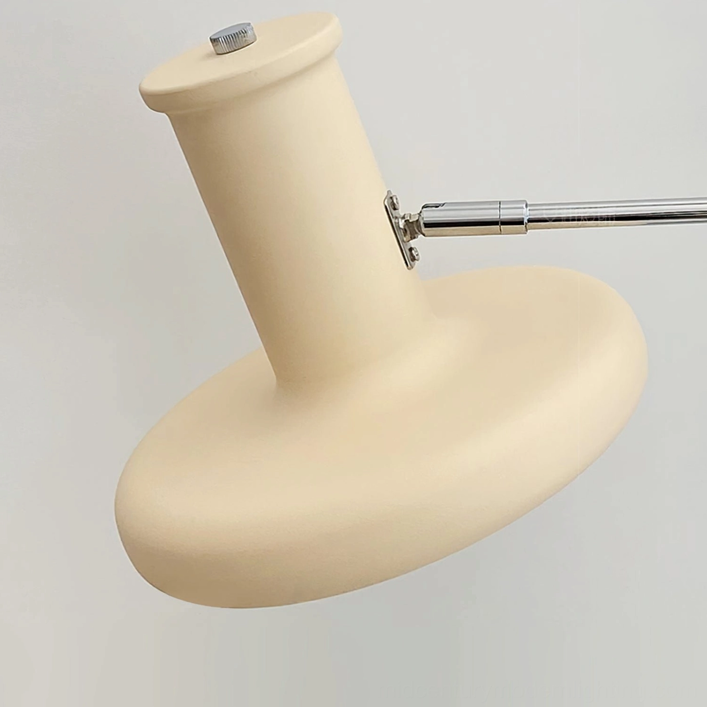 Close-up macro detail of mid-century wall lamp shade and chrome hardware assembly on white background