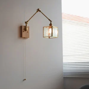 Articulated swing arm wall lamp installed in bedroom corner with warm brass arm, light wood base, and frosted glass shade creating ambient lighting