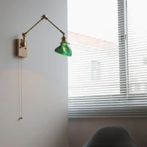 Swing arm wall lamp installed in mid-century modern home interior with louvered window, showing light wood finish and brass hardware