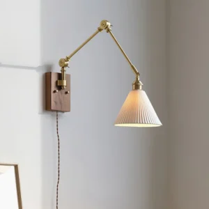 Illuminated swing arm wall lamp in corner setting showing ribbed ceramic shade and brass articulated arm