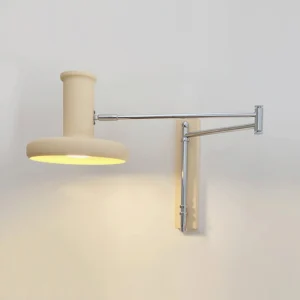Adjustable articulated arm wall lamp illuminated showing warm ambient light diffusion through cream fabric shade