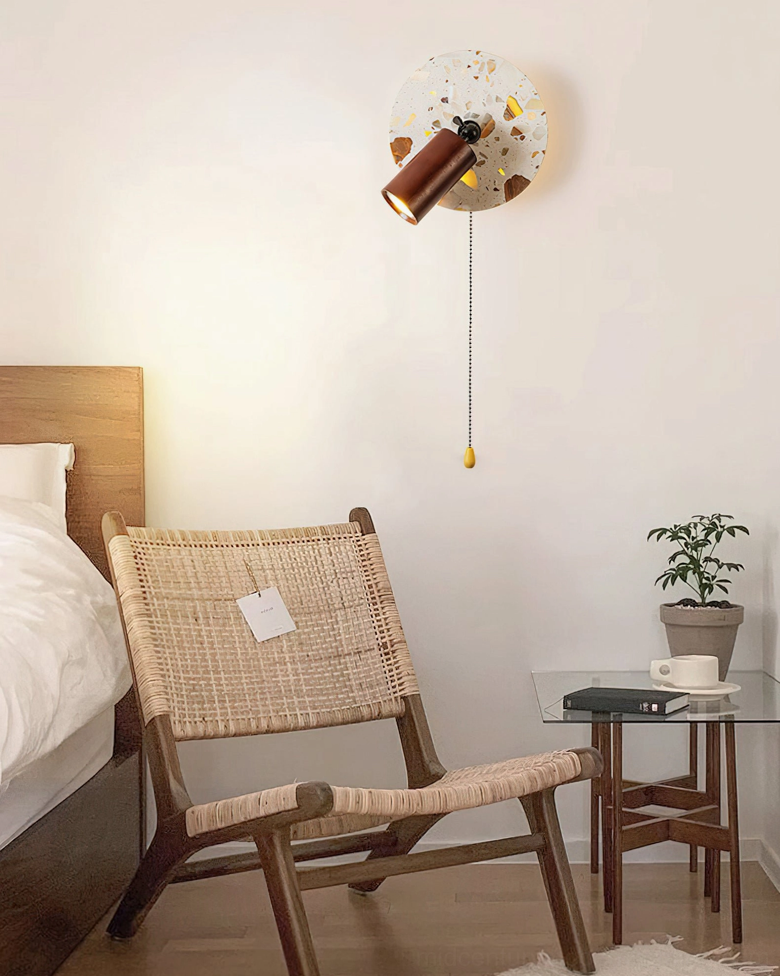 Swizzle terrazzo wall lamp in leisure bedroom corner paired with rattan chair and glass side table demonstrating mid-century modern styling