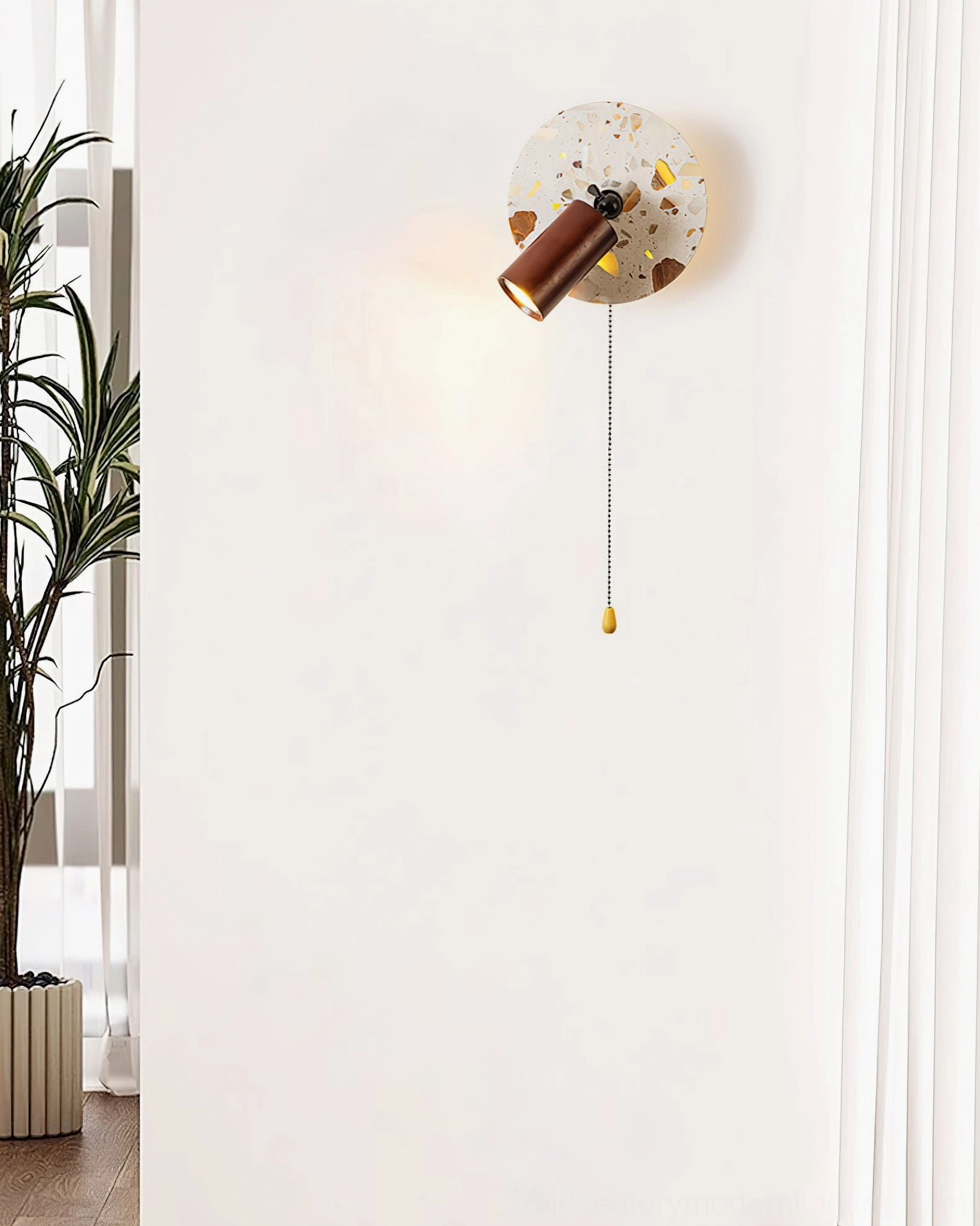 Swizzle terrazzo wall lamp installed on indoor corner wall with potted plant and simple home setting background