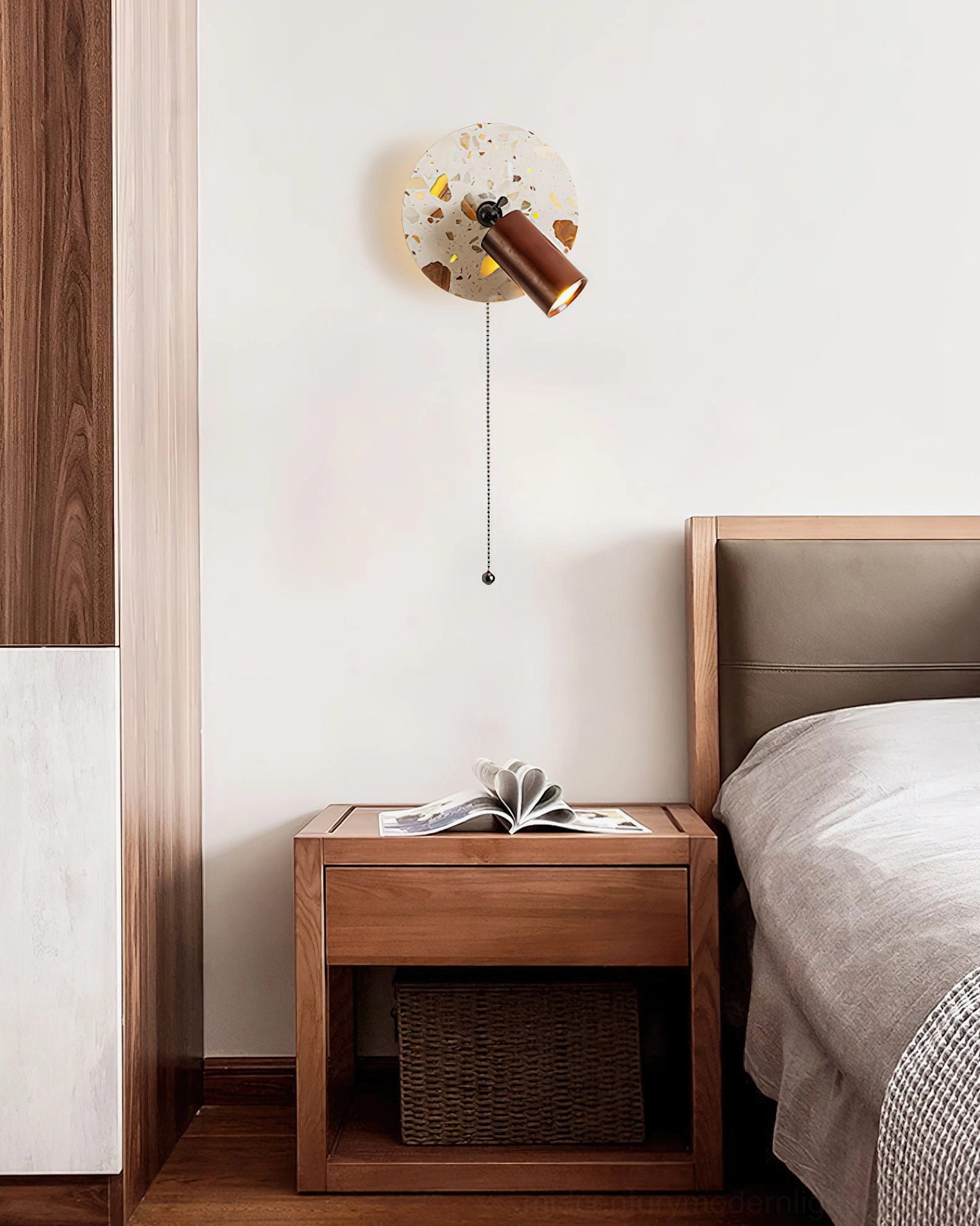 Swizzle wall lamp mounted in minimalist wooden bedroom with open book on nightstand and neutral tone home decor aesthetic