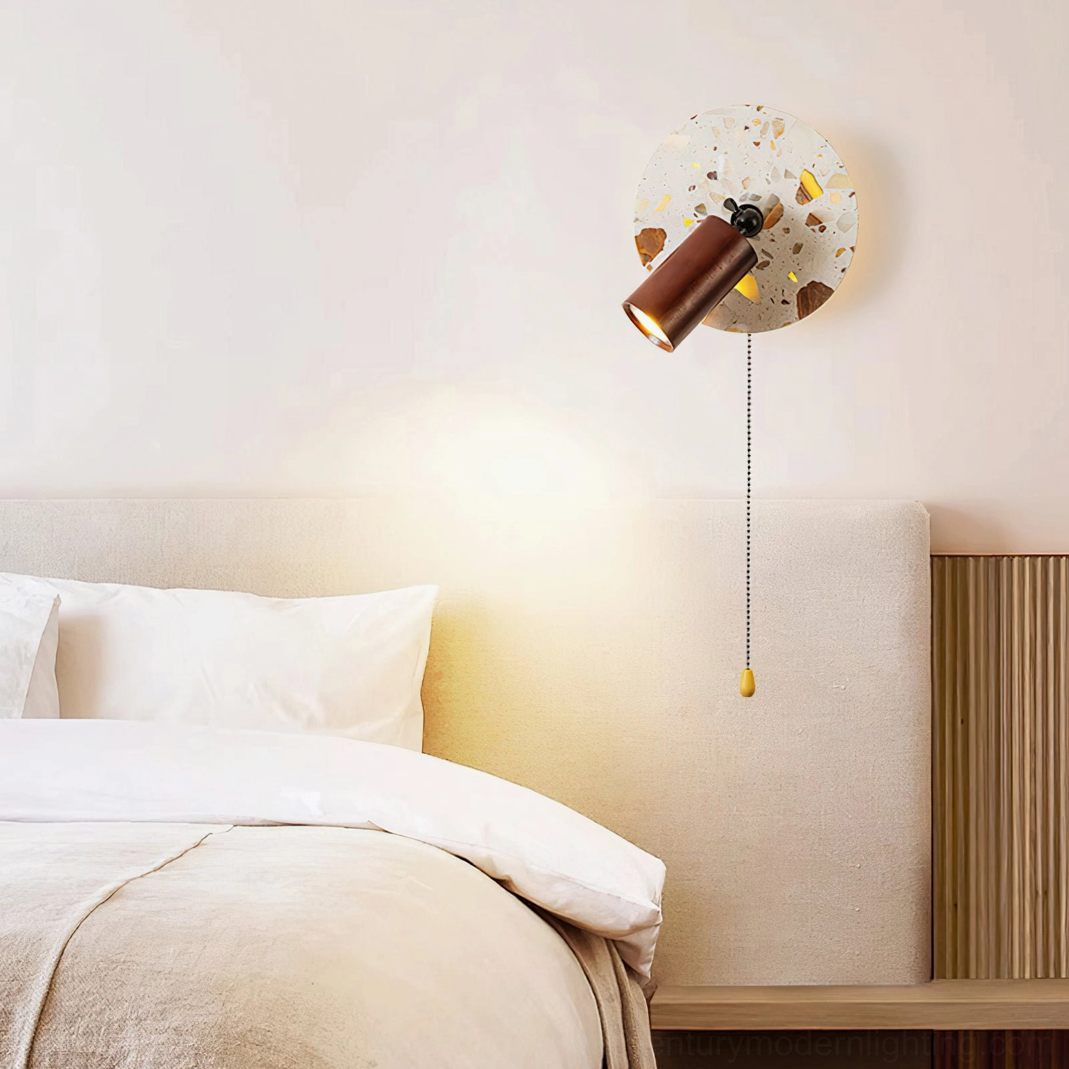 Swizzle terrazzo wall lamp close-up mounted on bedroom wall with bed backdrop showing warm glow and neutral interior design styling