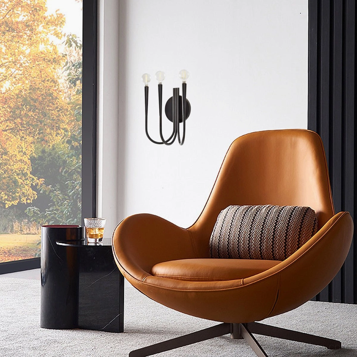 Matte black Swoop wall sconce in mid-century modern lounge setting with leather accent chair and contemporary furnishings