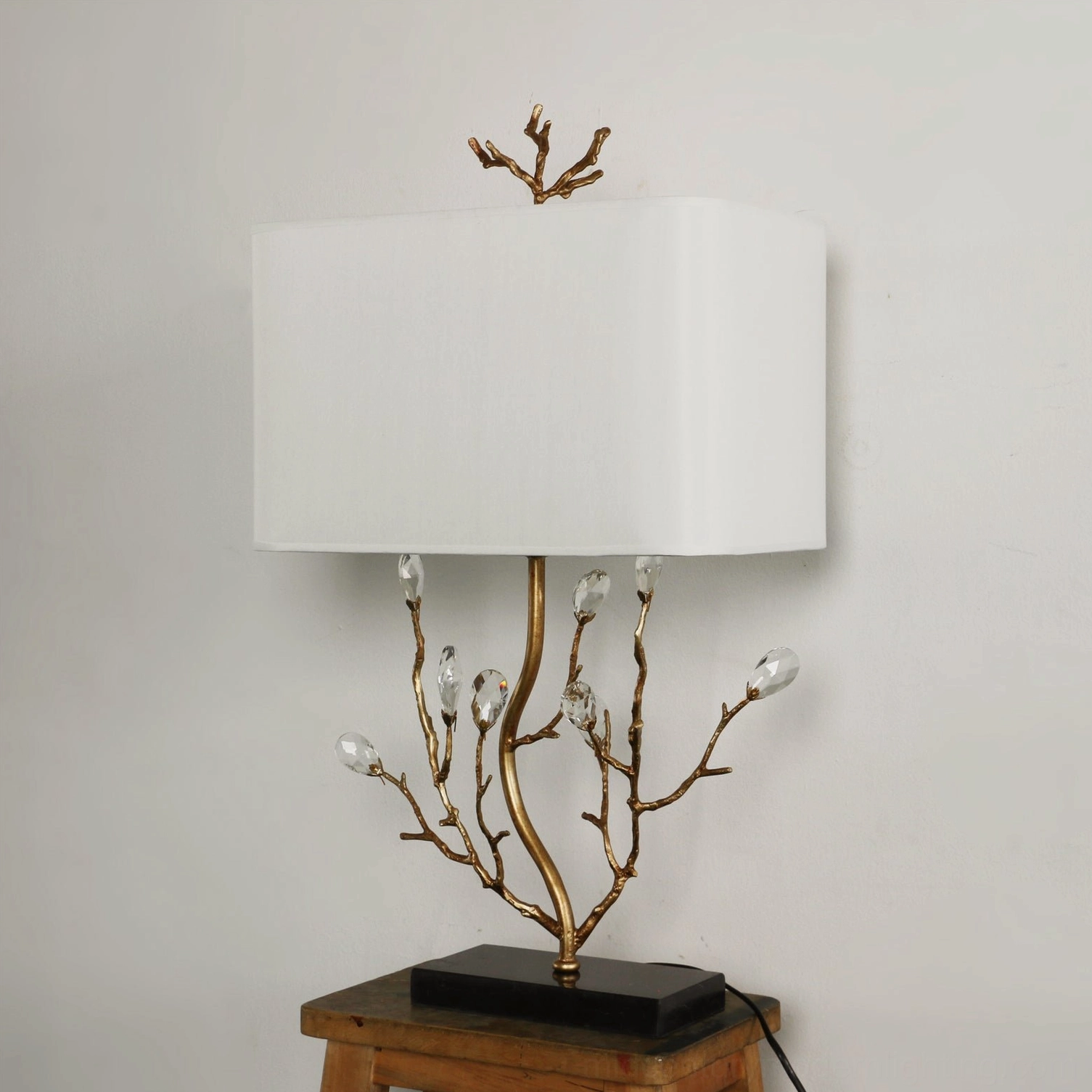 Unlit Sylvia brass branch table lamp three-quarter view showing crystalline ornament details against warm wall backdrop