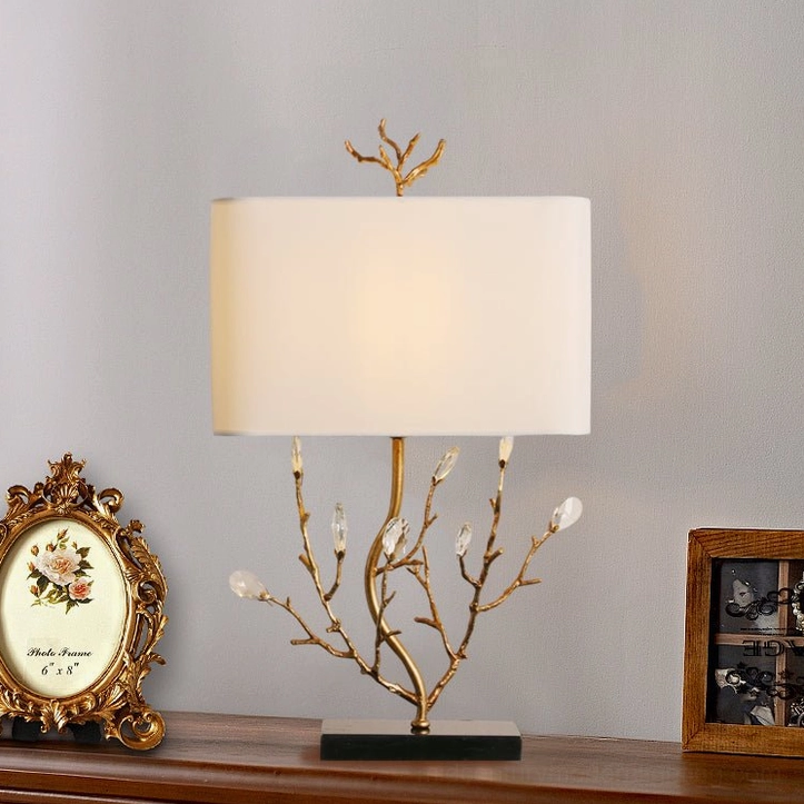 Sylvia brass table lamp side view on wooden table with vintage decorative frame props, mid-century modern styling
