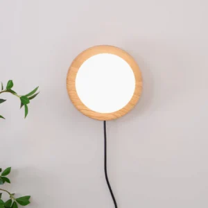 Unlit Tablet plug-in wall lamp mounted on light wall with decorative green plants showing wood frame and frosted glass shade