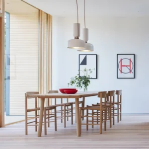 Pair of white Taeuber pendant lights in modern dining room with wooden table and contemporary wall art
