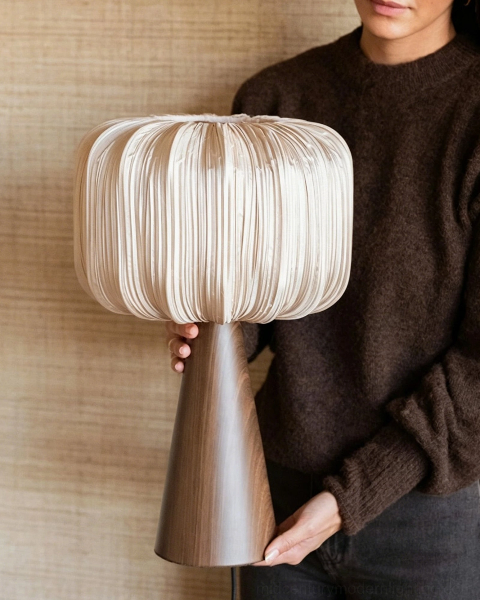 Talia pleated table lamp held in hand against textured wall backdrop demonstrating size and scale with person model