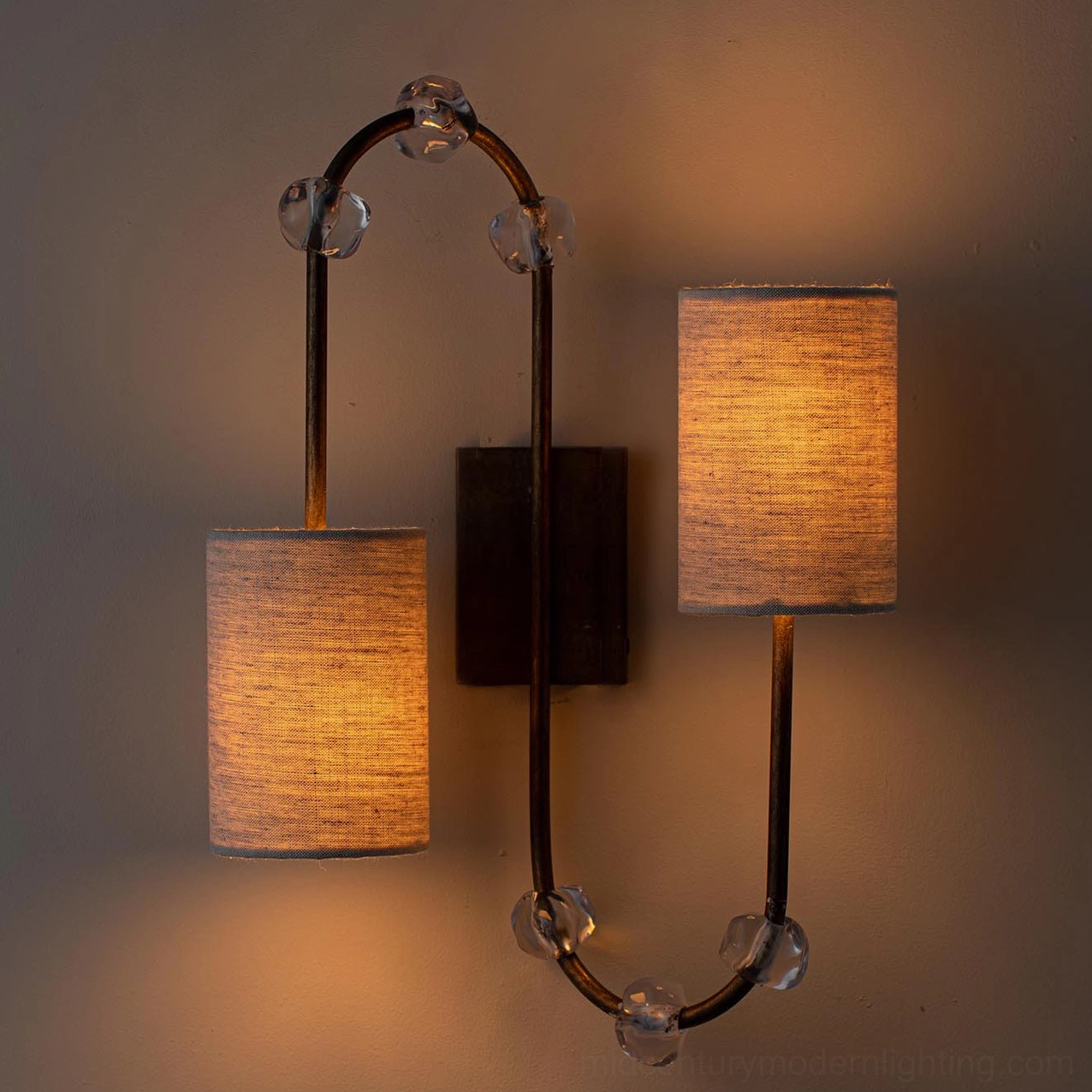 Tanyel twin-head wall sconce with dark metal frame and crystal details, illuminated warm ambiance