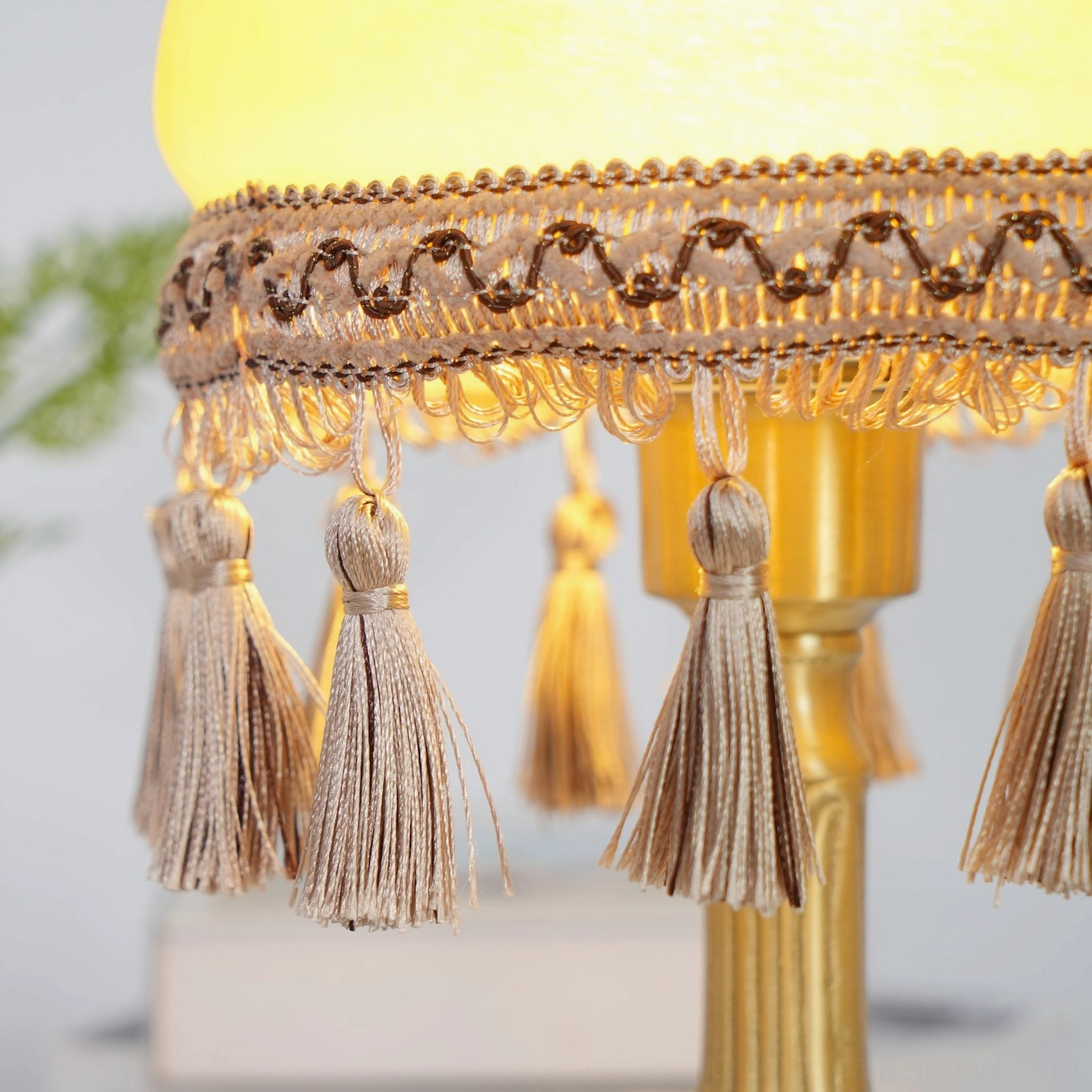 Side view of tassel ornament, embroidered lace trim, and polished golden brass lamp frame