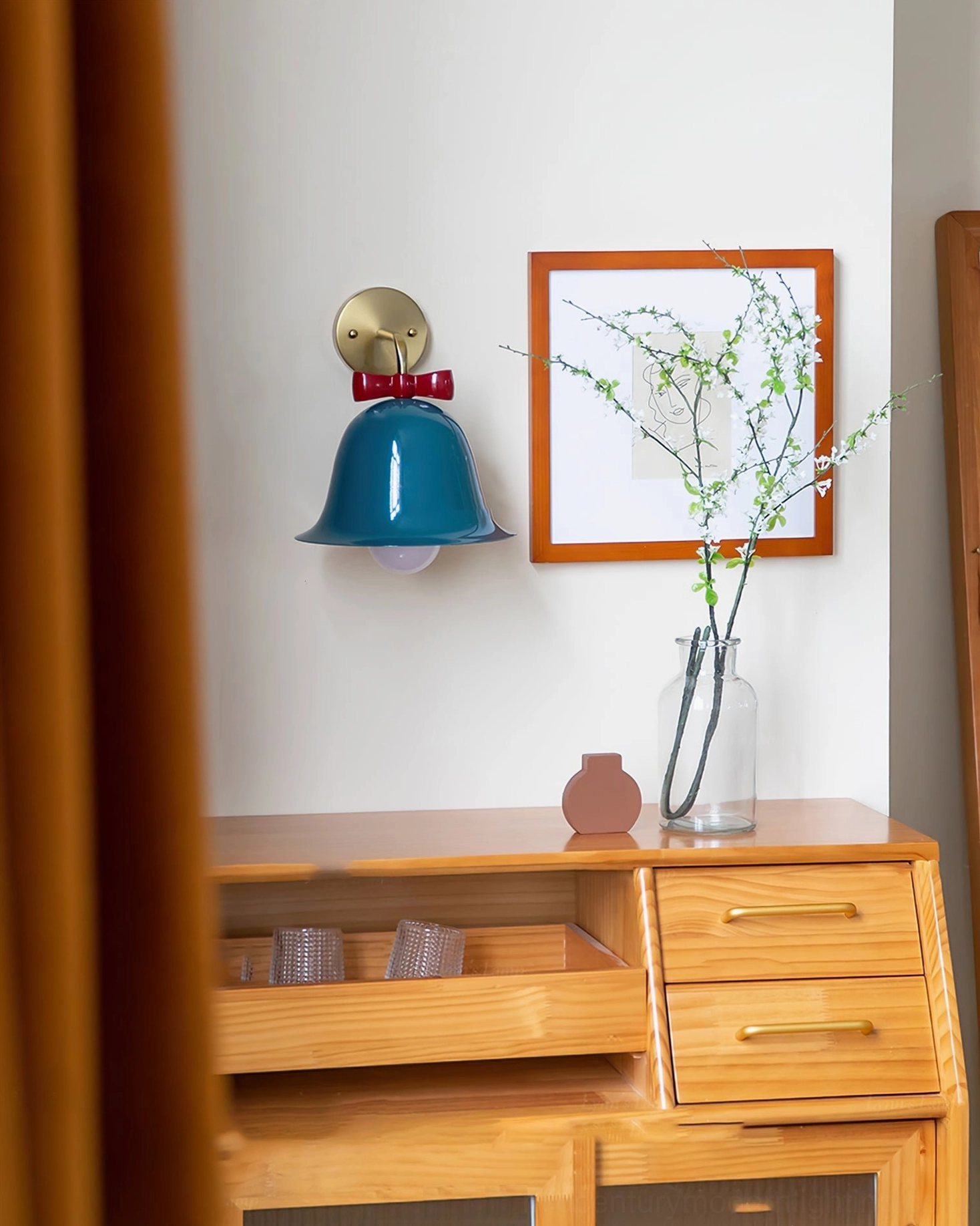 Teal blue Bow Bell Wall Lamp above bedroom dresser with framed art in warm minimalist vintage setting
