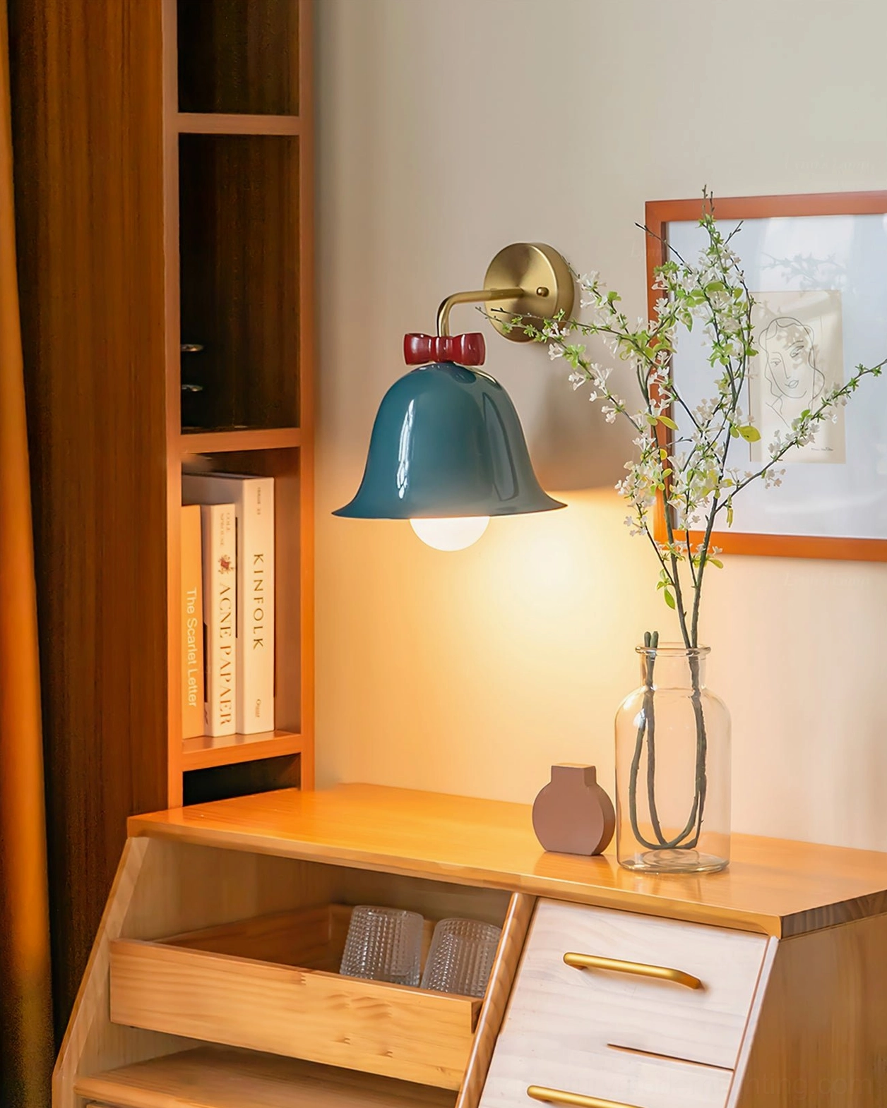 Teal blue Bow Bell Wall Lamp mounted above vanity desk with wooden furniture and fresh flowers