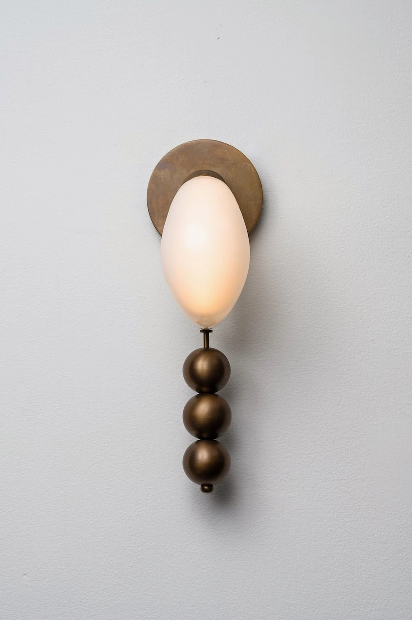 Teardrop glass wall sconce with dark bronze framework and three spheres, warm glowing ambient light close-up detail