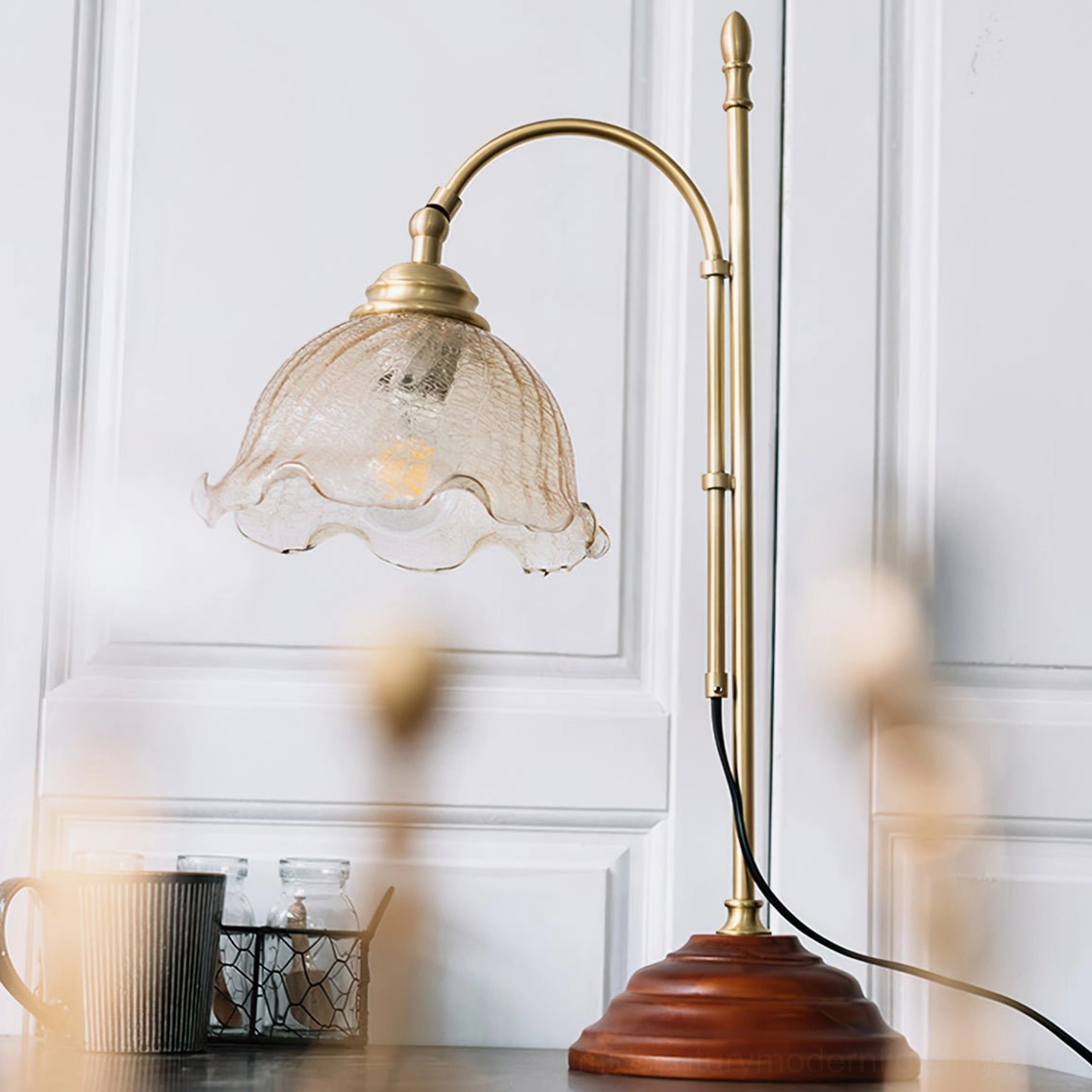 Textured glass lamp with brass hardware and brown wood base against white paneled wall, front angle view