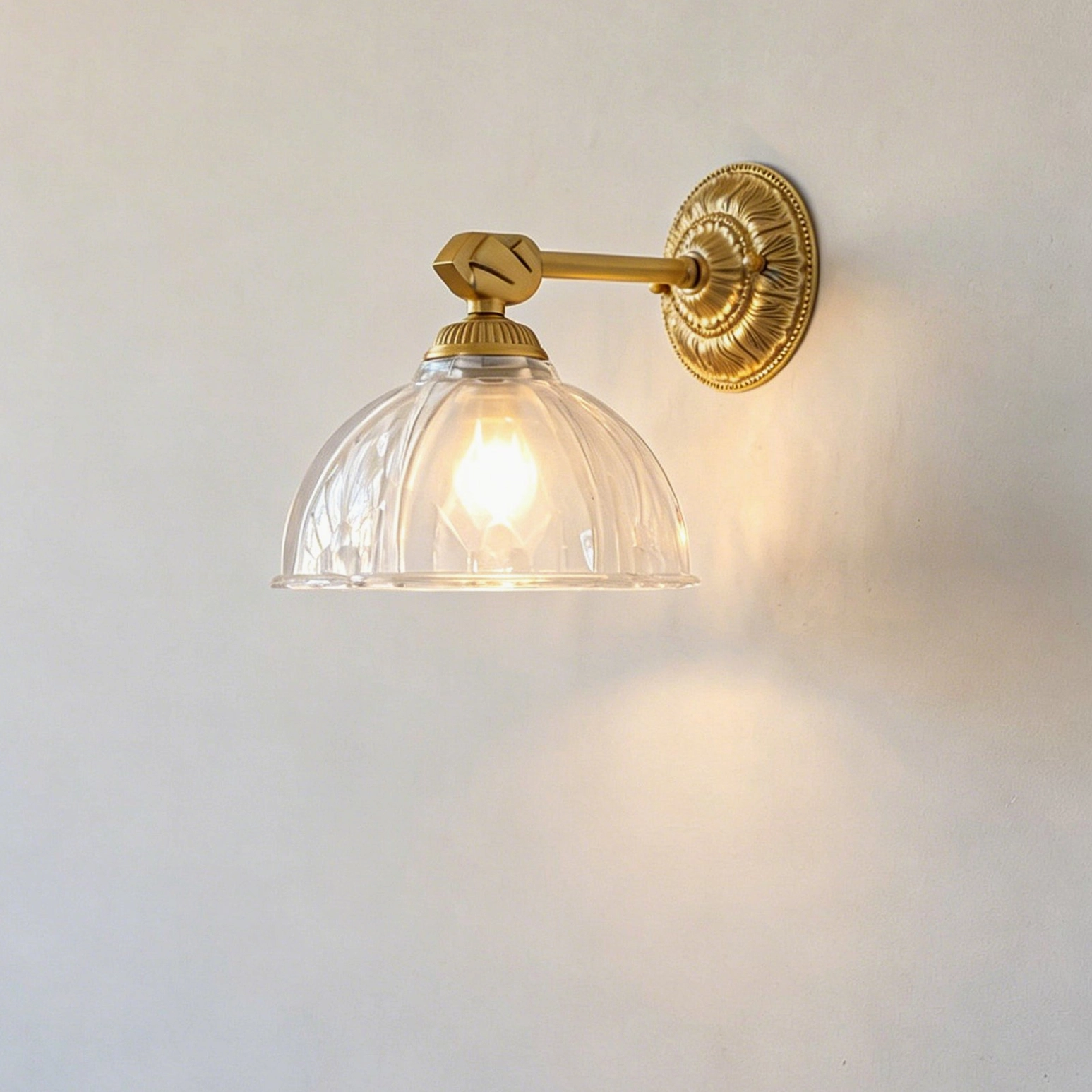 Thayer vintage brass wall sconce with hand-embossed botanical glass shade casting dappled shadow