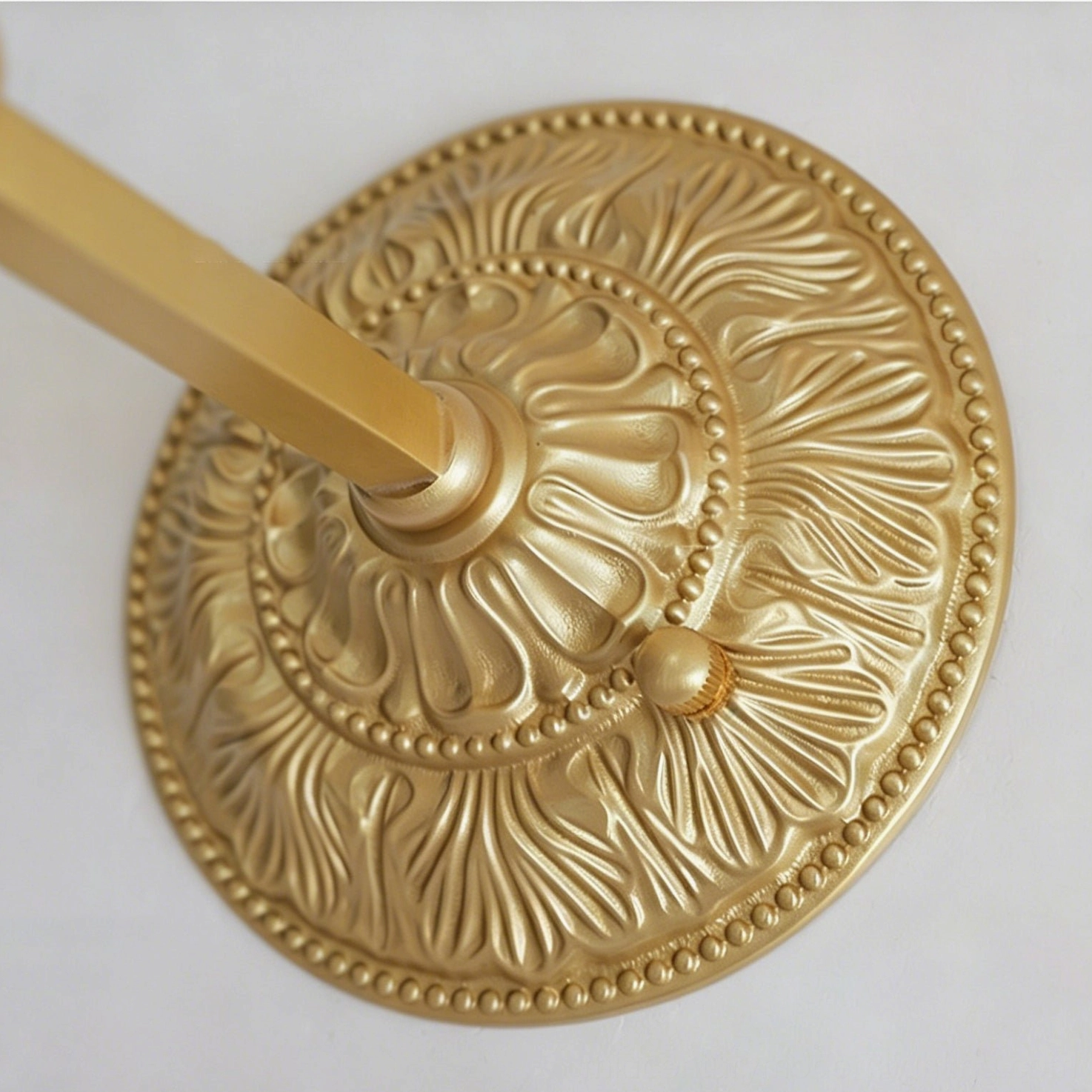 Thayer vintage brass sconce illuminated casting botanical shadow patterns on wall surface