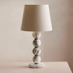 Thelma table lamp close-up detail showing stacked natural marble spheres and bronze metal collars with tapered linen shade