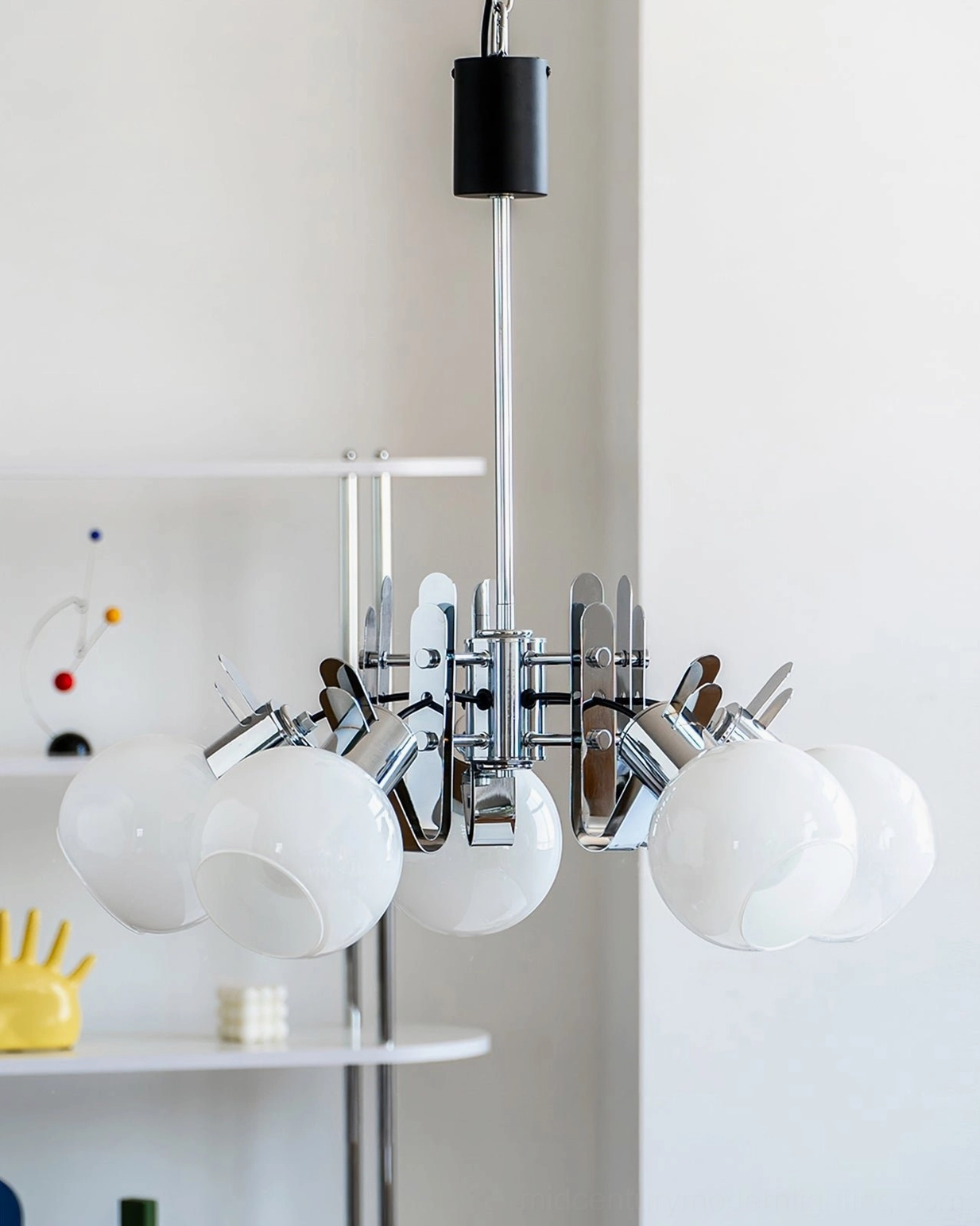 Three-head geometric glass chandelier displayed on white shelf with polished chrome framework