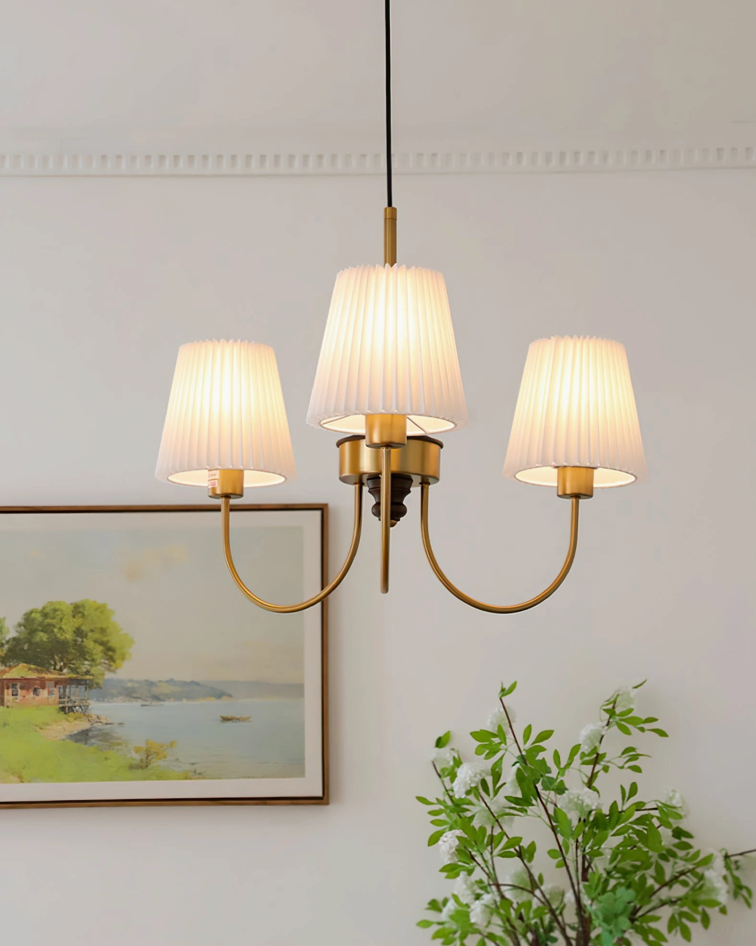 3-head wood chandelier glowing warmly in bedroom with landscape art and greenery