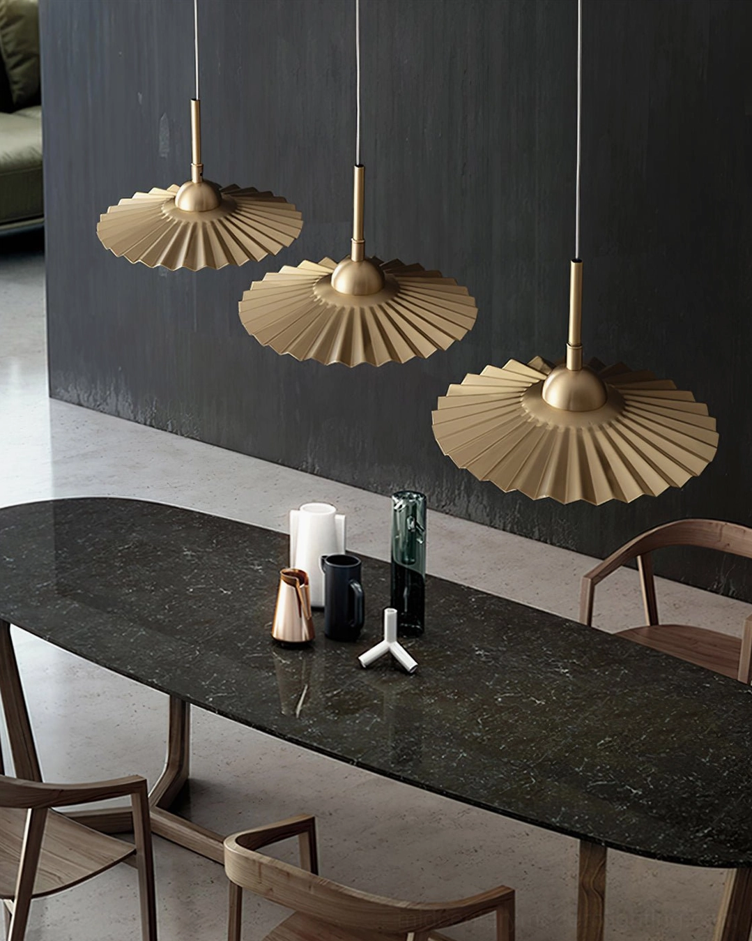 Set of 3 plié pendants suspended above luxury dining room with dark accent wall paired with warm brass illumination