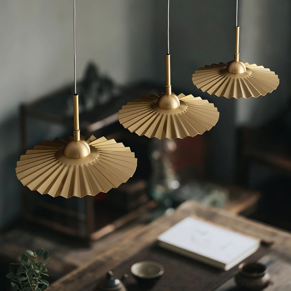 Set of 3 plié pendant lamps clustered above vintage wooden dining table creating warm modern rustic aesthetic