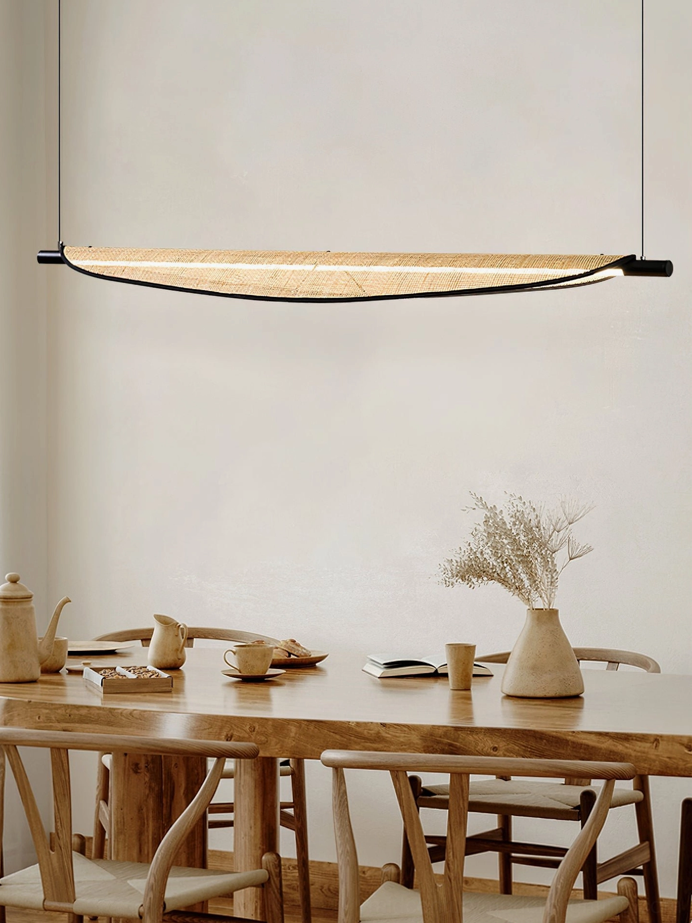 Thula rattan chandelier hanging over large wooden dining set in japandi style interior design