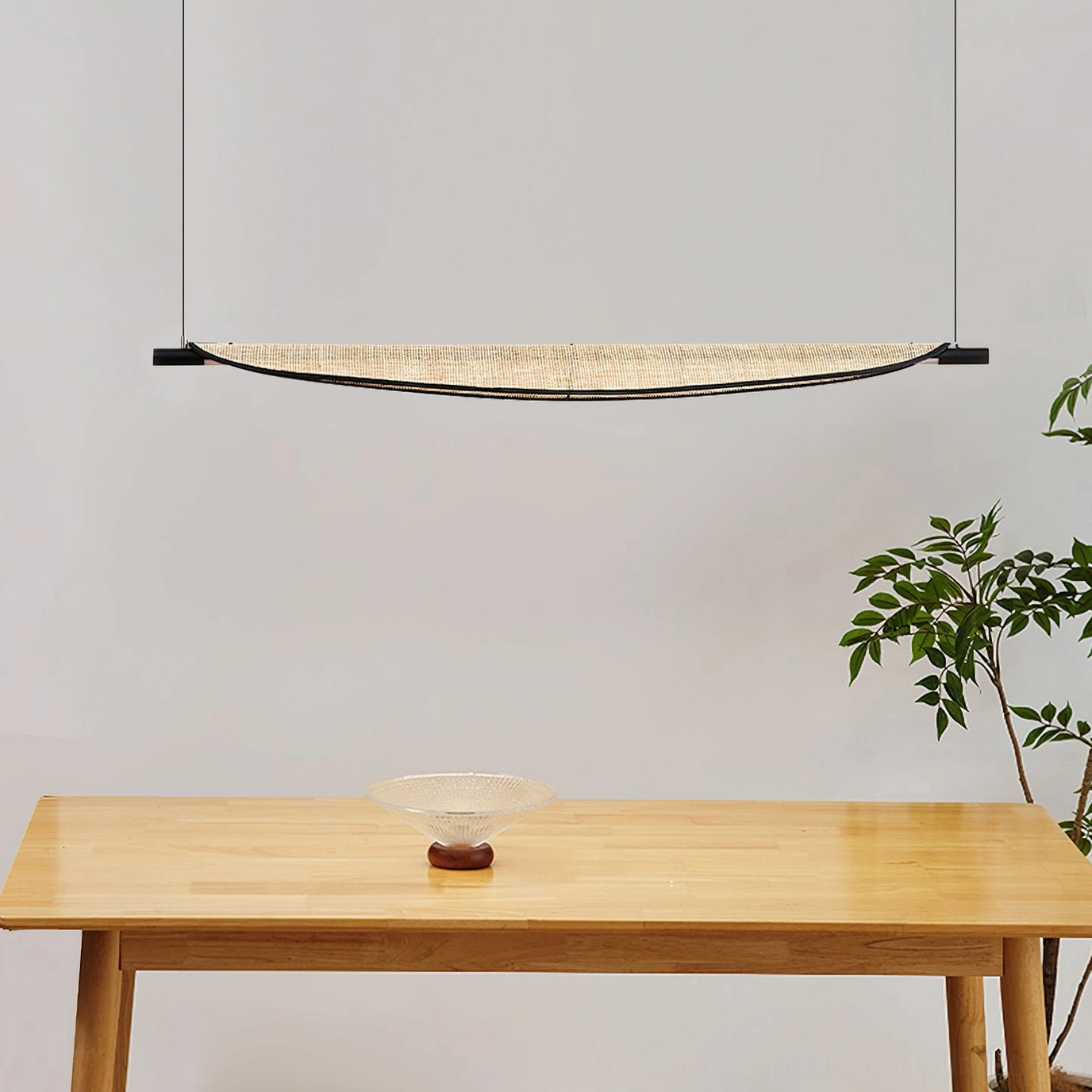 Thula rattan pendant light suspended over wooden dining table in wabi-sabi inspired interior