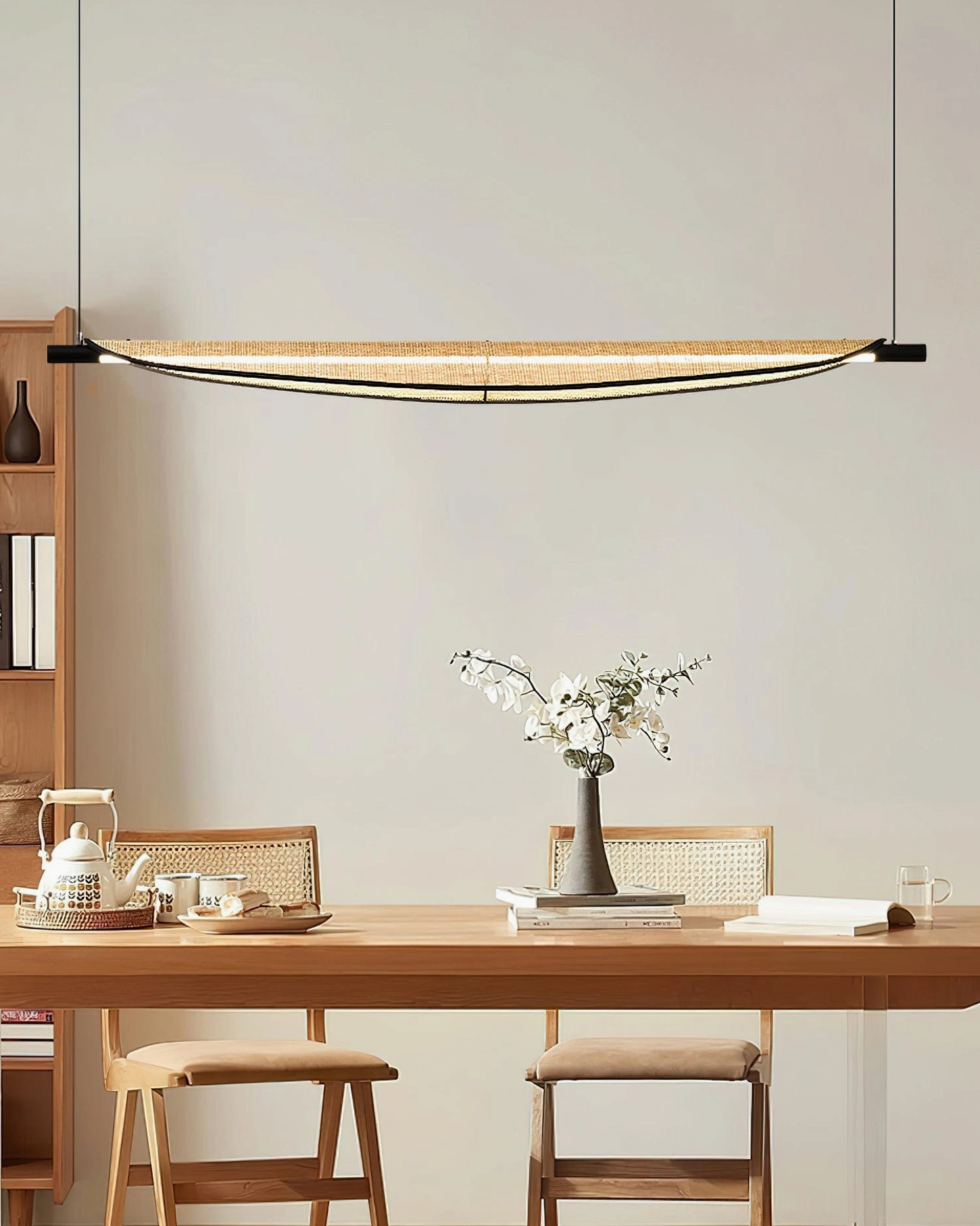 Thula linear rattan chandelier overhead view in minimalist dining space with white floral decor