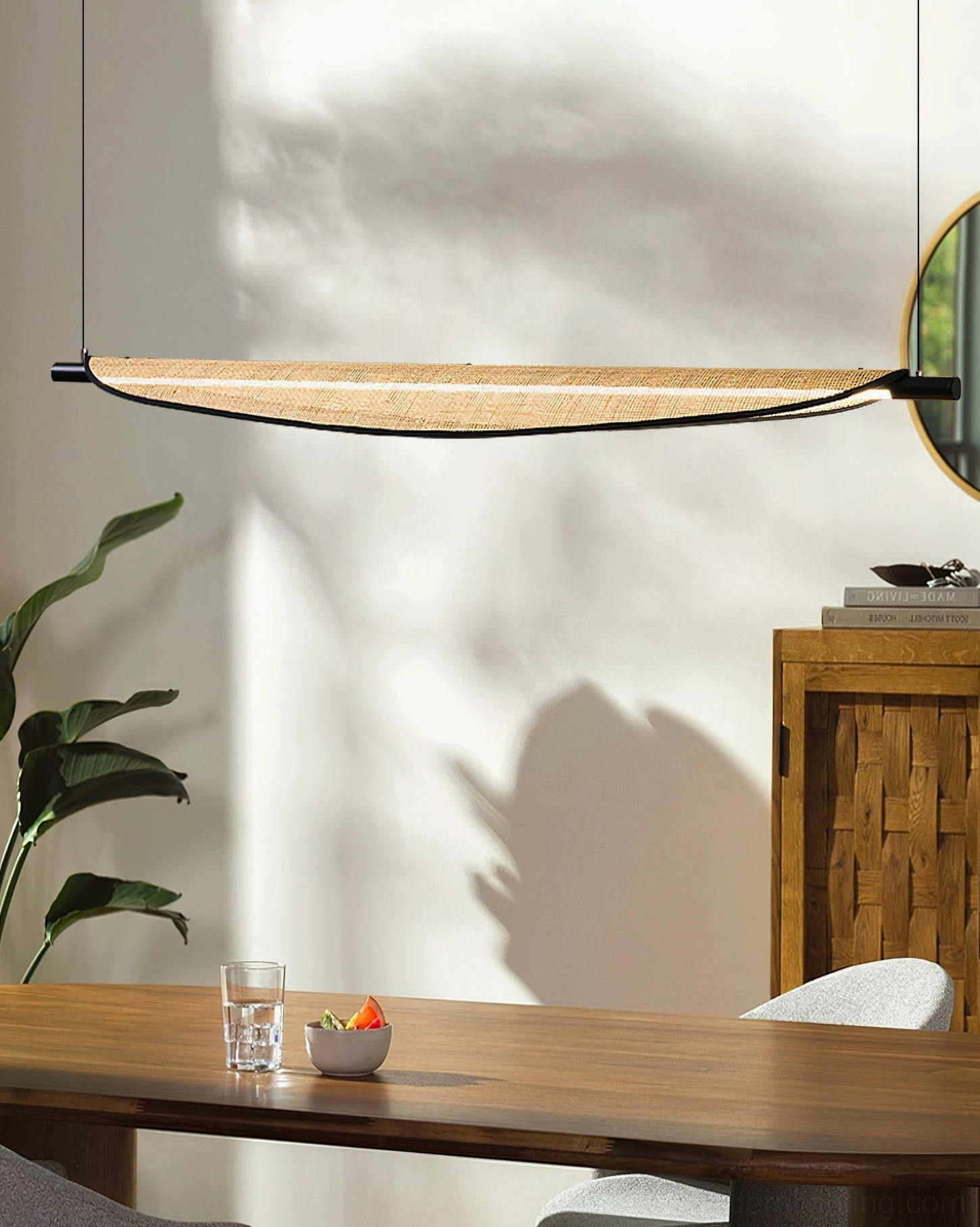 Thula linear pendant light side angle view over rustic wooden dining table with warm ambient lighting
