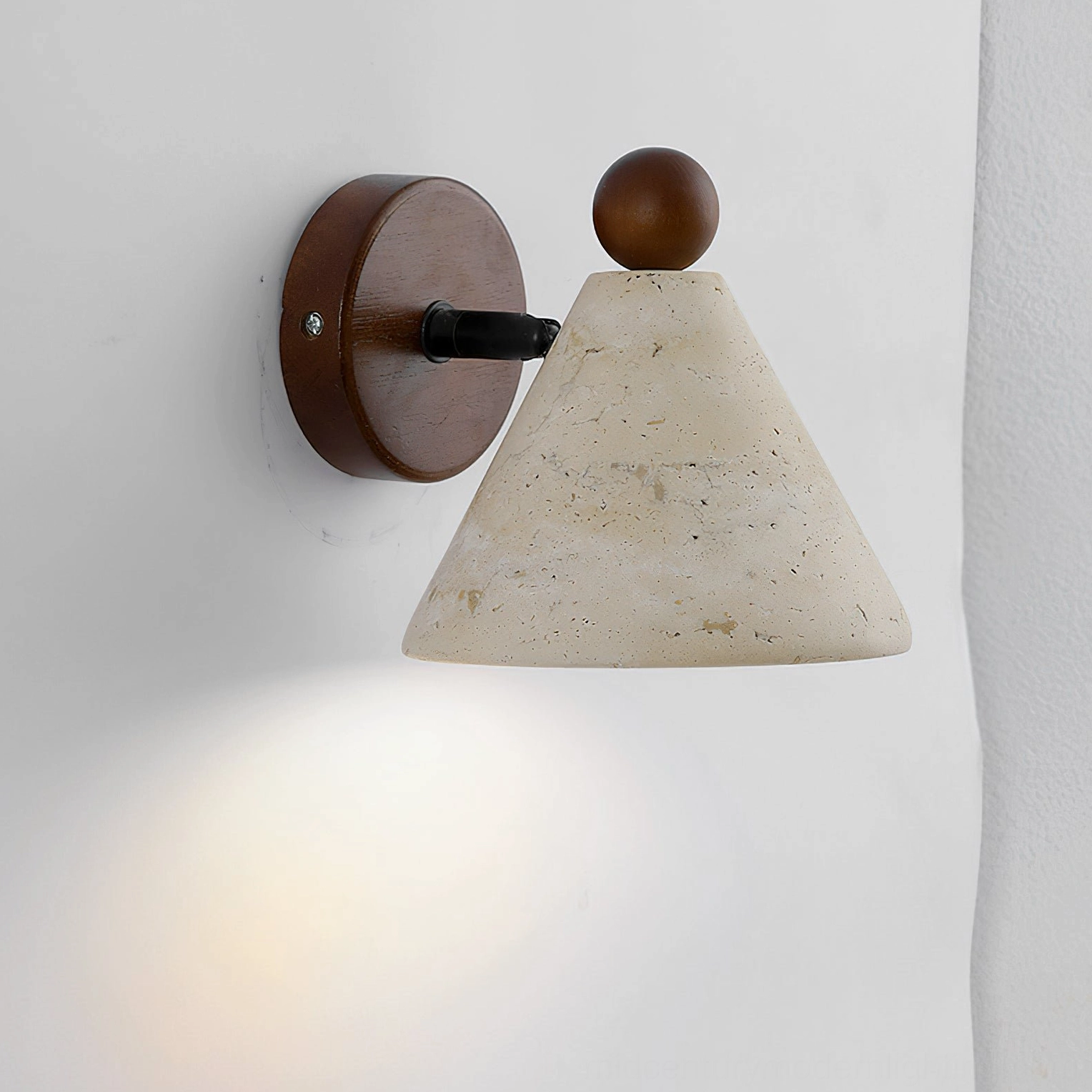 Tiber travertine wall sconce showing natural stone pitting and mineral veining in studio lighting