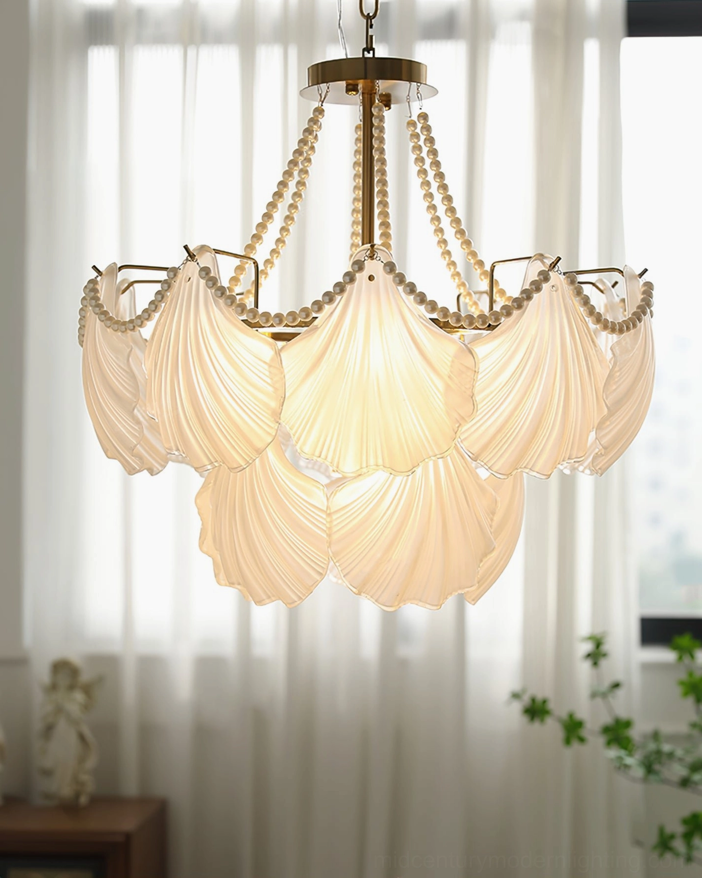 Tiered shell glass chandelier in window nook with warm yellow ambient glow and brass frame detail