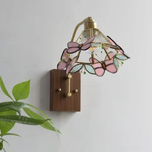 Close-up detail of pink stained glass butterfly motifs and textured glass shade with brass frame accents