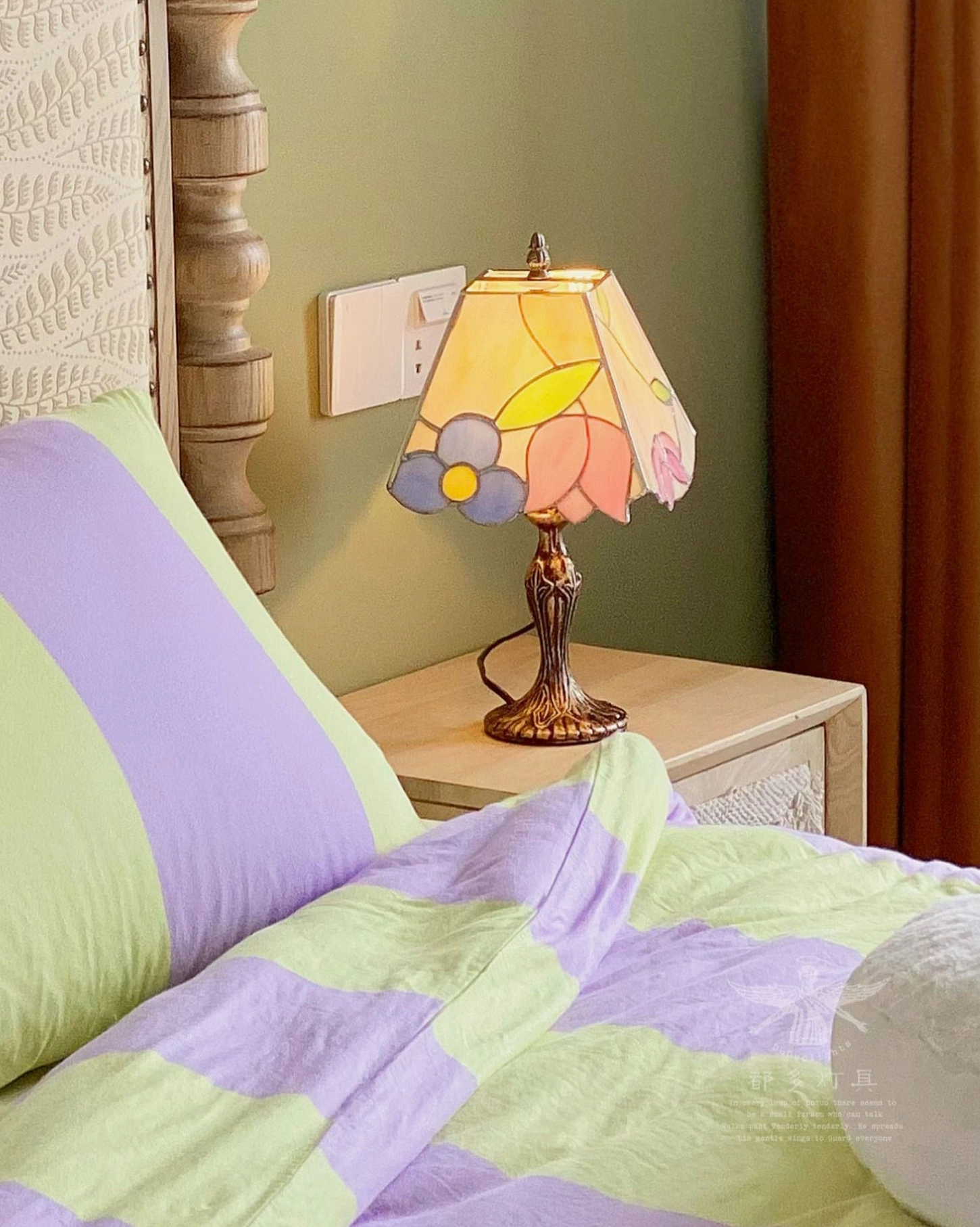 Handcrafted Tiffany table lamp in bedroom with green accent wall and striped bedding