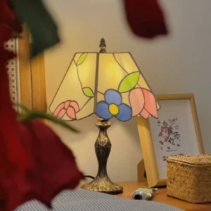 Vintage Tiffany lamp with floral stained glass shade on bedroom nightstand with rose foreground