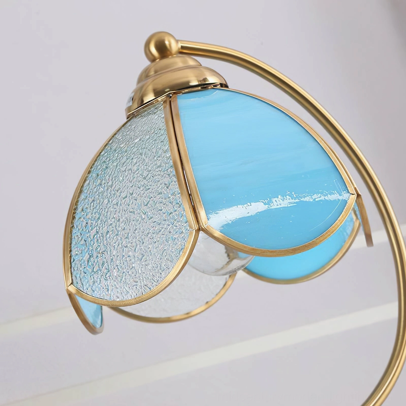 Close-up side view of blue stained glass Tiffany lamp shade with textured frosted glass panels and brass frame