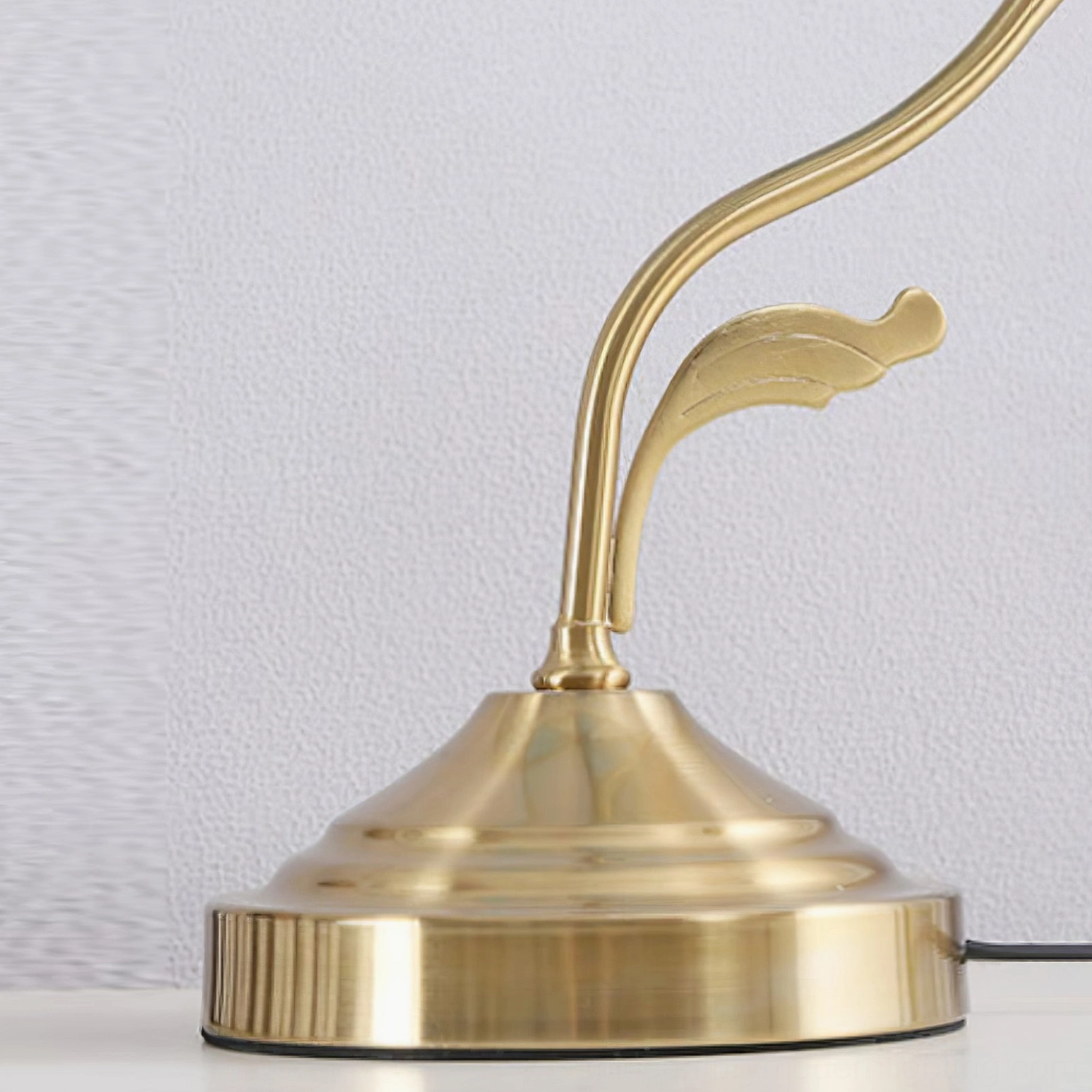 Tiffany table lamp base and stem detail showing solid brass round base with decorative leaf-shaped metal armature