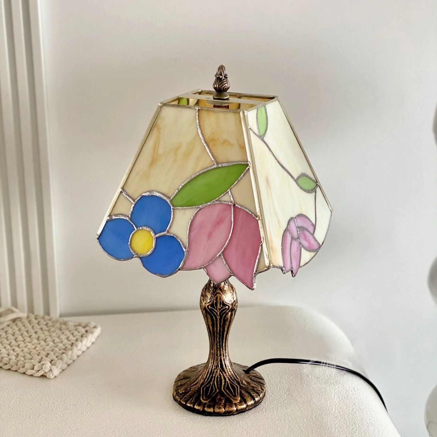 Vintage Tiffany style lamp with floral stained glass shade on white upholstered daybed