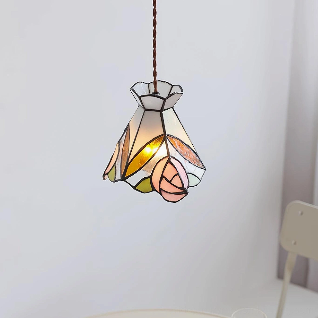 Illuminated Tiffany pendant light with warm glow cast on white chair in minimalist modern interior