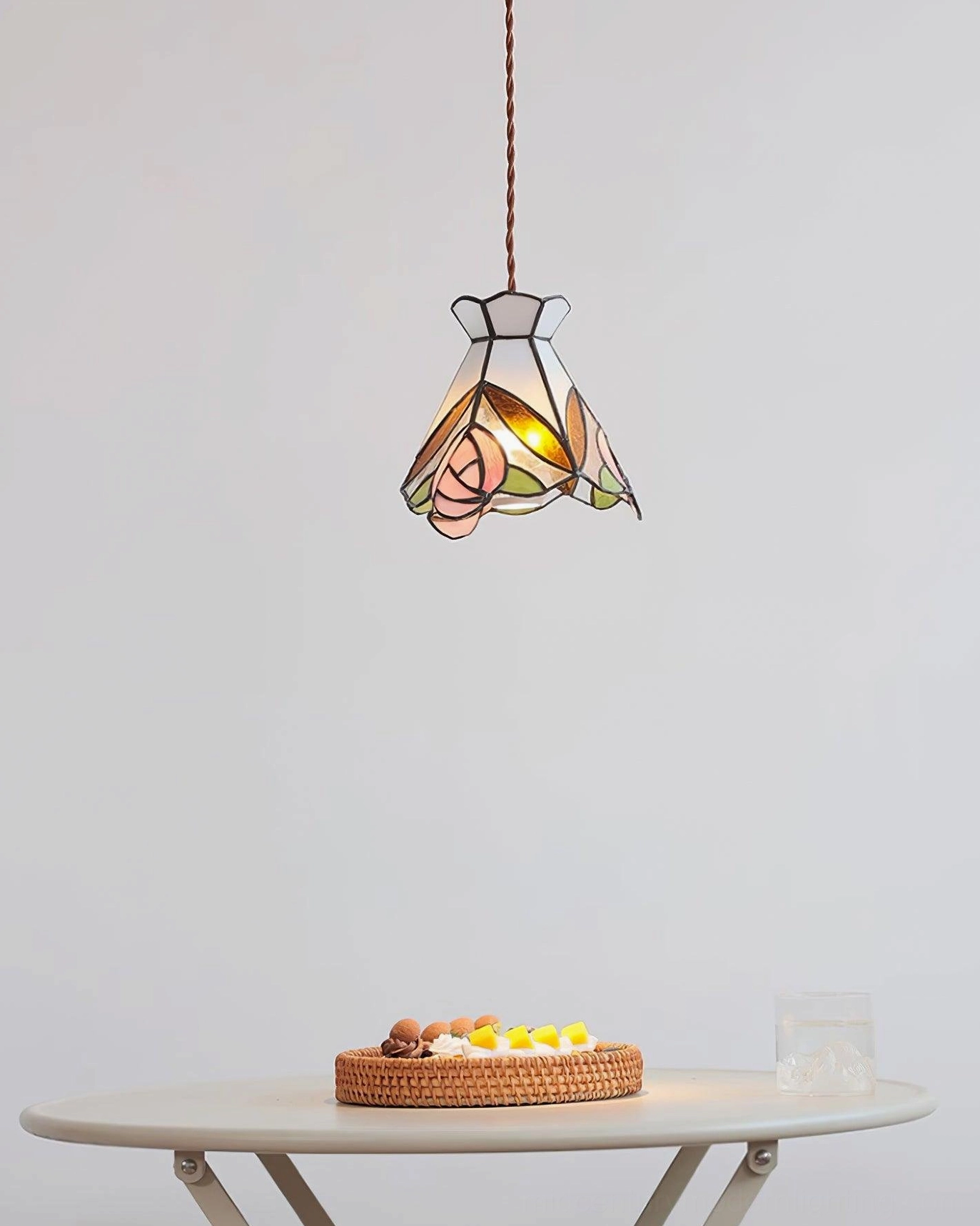 Compact Tiffany rose pendant light fixture glowing in minimalist dining space side view