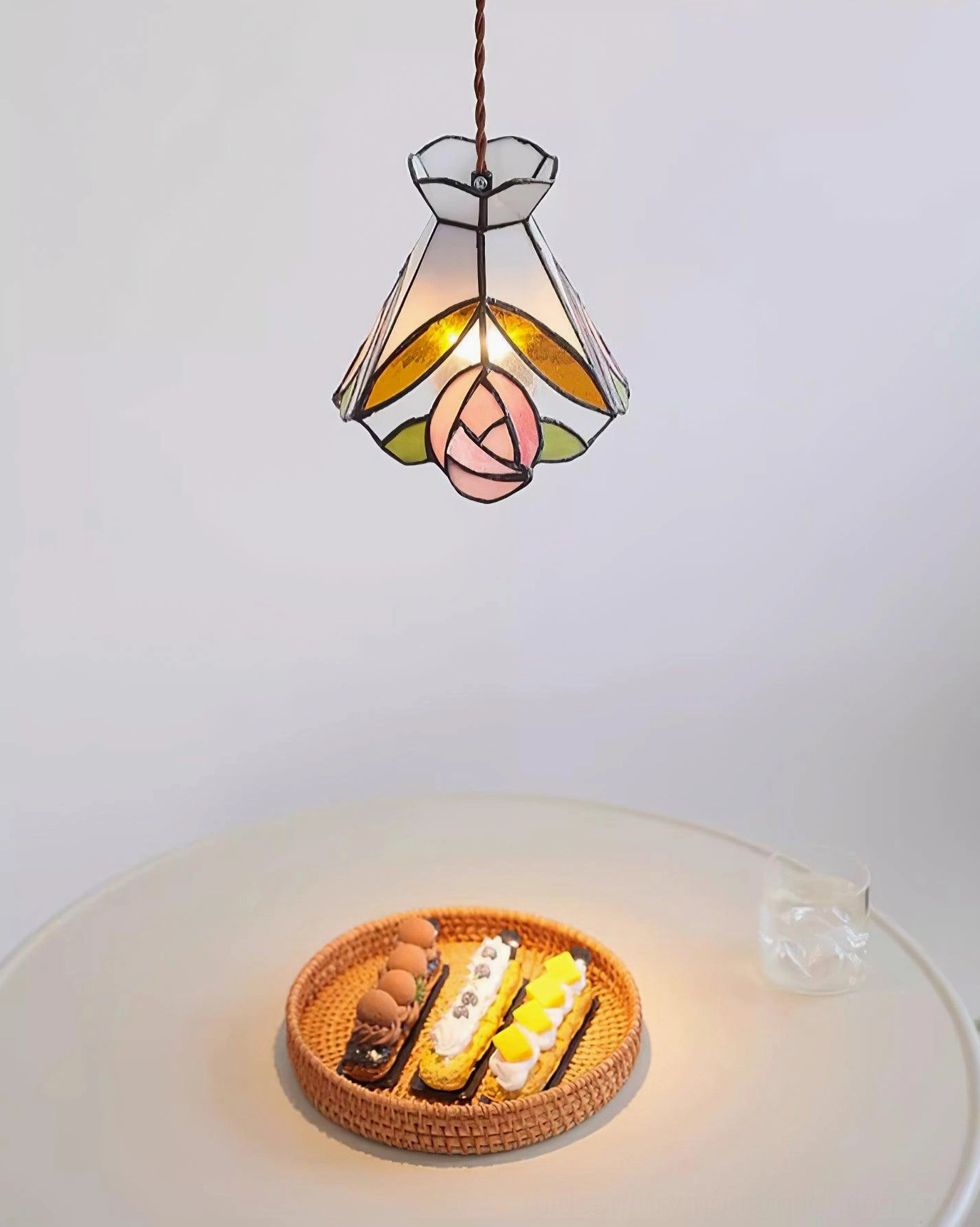 Rosebud Tiffany pendant casting soft filtered light through pink and yellow stained glass panels