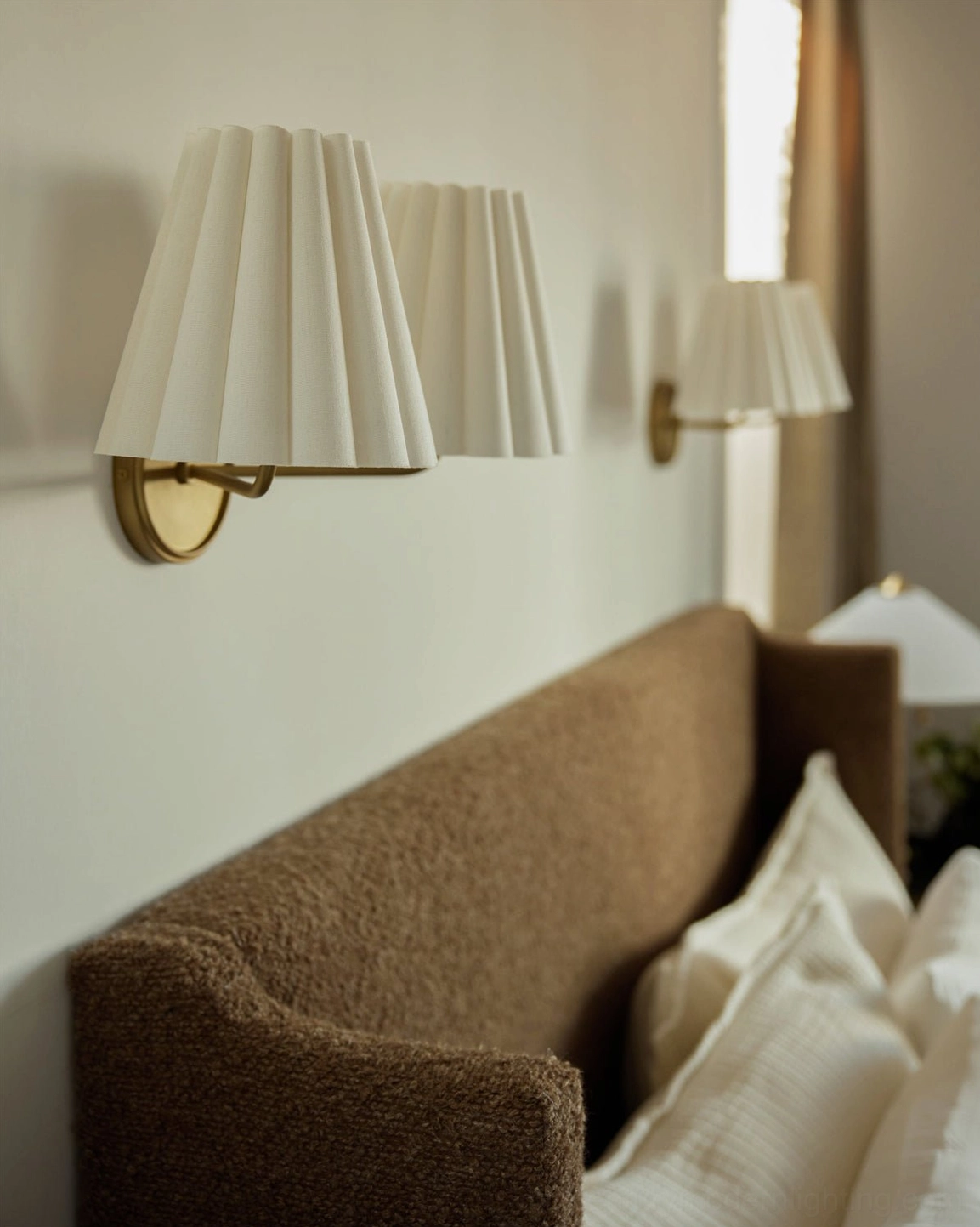 Gold brass Tilia wall sconces with pleated shades in cozy living room with modern minimalist seating
