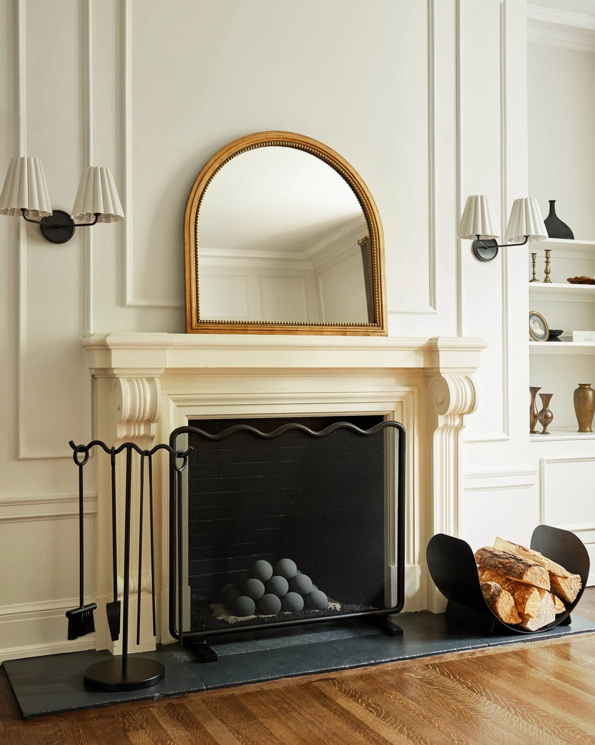 Pair of black Tilia wall sconces flanking vanity mirror in traditional living room with fireplace
