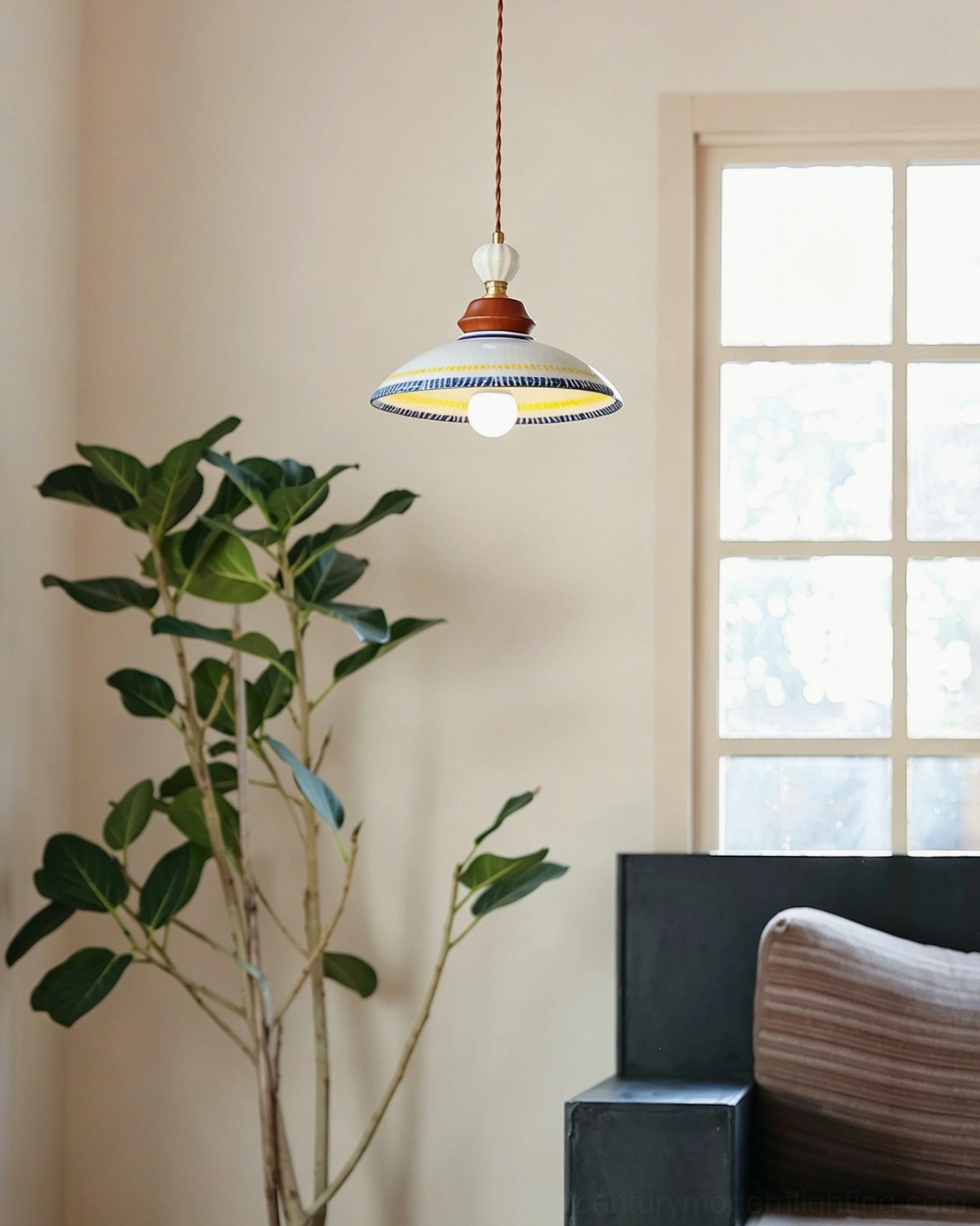 Tilly handcrafted ceramic pendant with brass-toned and walnut wood fixture top, displayed in cozy living room with grid window and green foliage