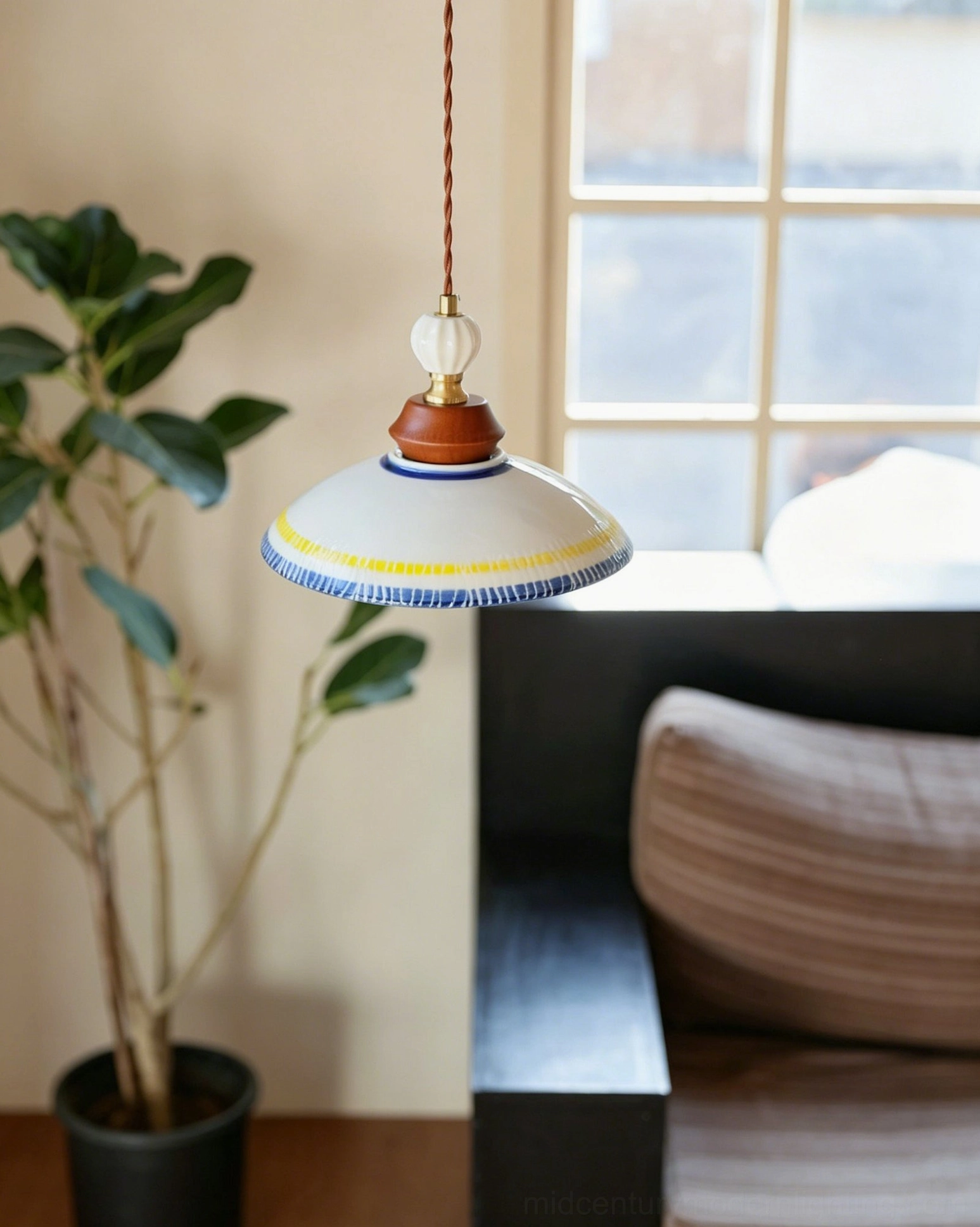 Tilly ceramic pendant shade with hand-striped rim and fabric suspension cord hanging near living room seating area with large window and potted plants